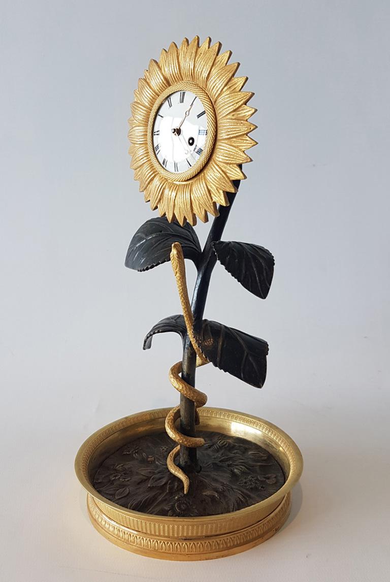 A sublime French Empire sunflower clock in original fire or mercury gilt ormolu and patinated bronze. Wonderful detail in this sweet clock, from the detailed ormolu base, the patinated bronze centre showing flowers, to the snake, curling its way up