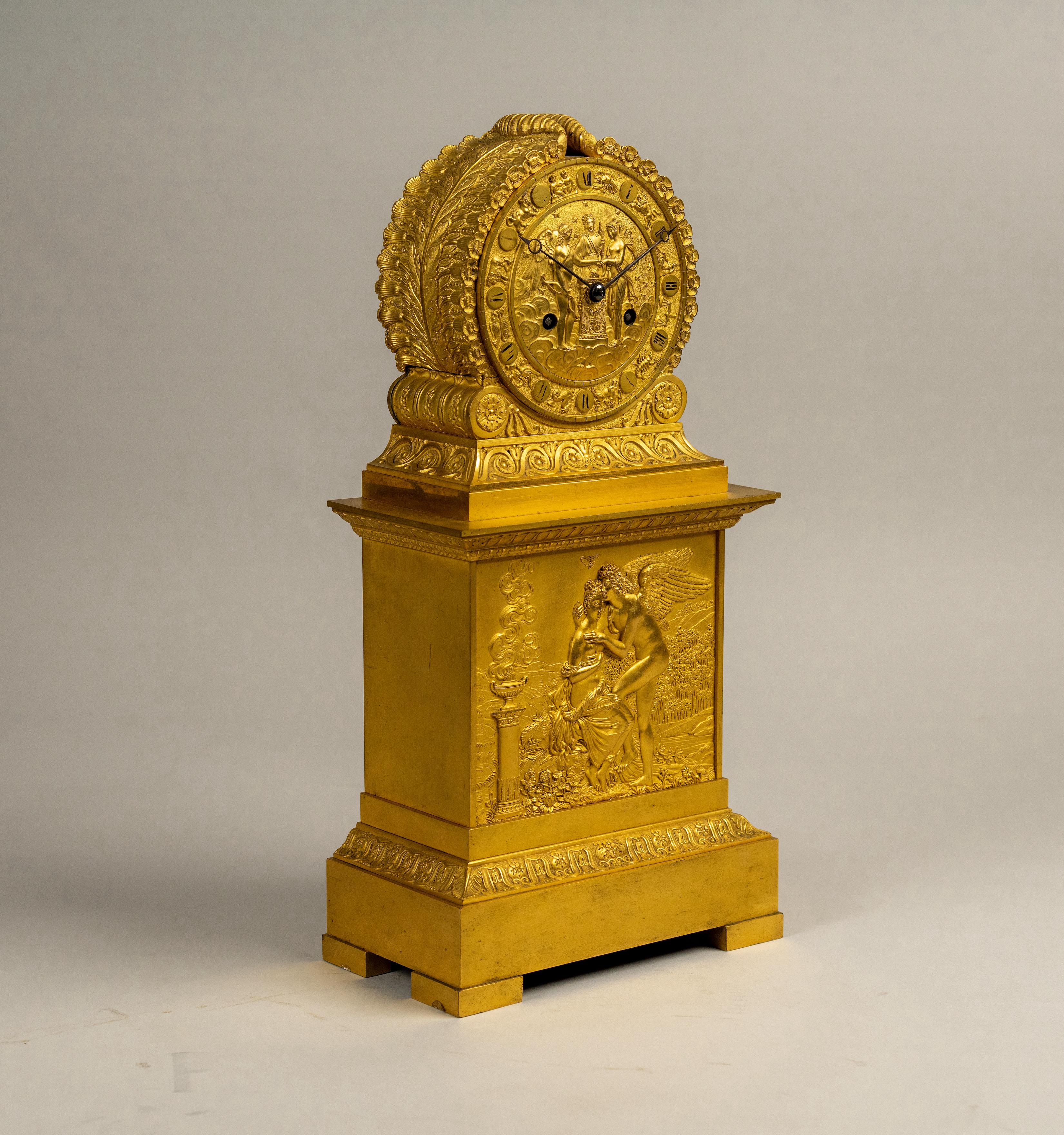 Exquise pendule de cheminée en bronze doré ciselé à la main de style Empire français du début du XIXe siècle. Elle repose sur des pieds en équerre et une base rectangulaire. Au-dessus, une superbe plaque en médaillon représentant Psyché et Cupidon