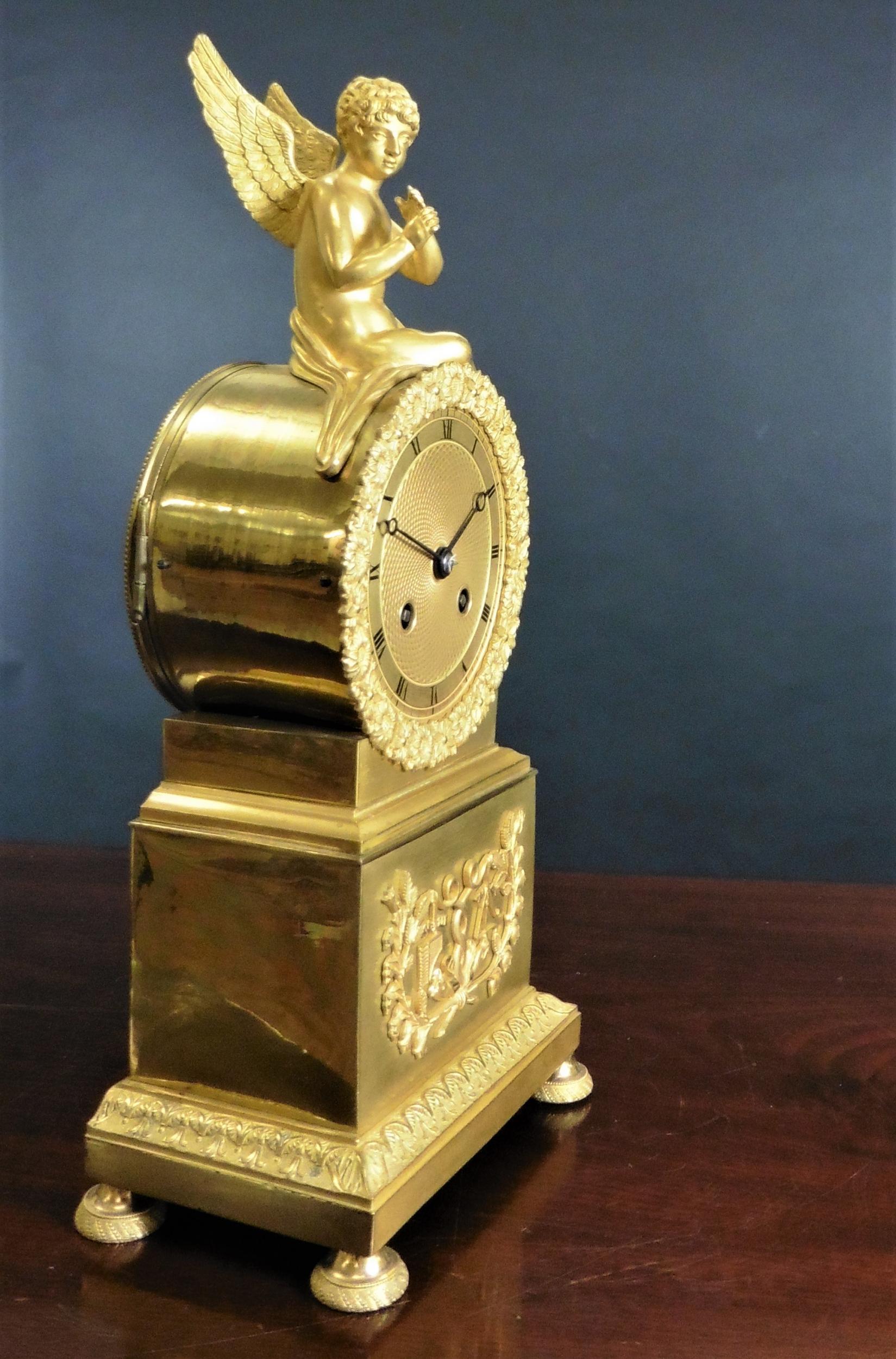 Ormolu French Empire clock, drumhead case with applied frieze decoration to the base, standing on turned and engraved feet. 

Superb engine turned dial centre, the gilded dial with Roman numerals, original hands and floral cast bezel surround.