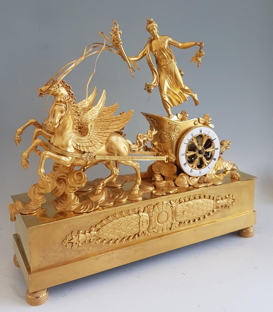 Belle pendule de cheminée ancienne en bronze doré Empire français représentant un char tiré par deux chevaux ailés portant le char avec une figure féminine. Cette superbe horloge représente Aurore tirée dans le ciel par ses chevaux ailés ou Pégase
