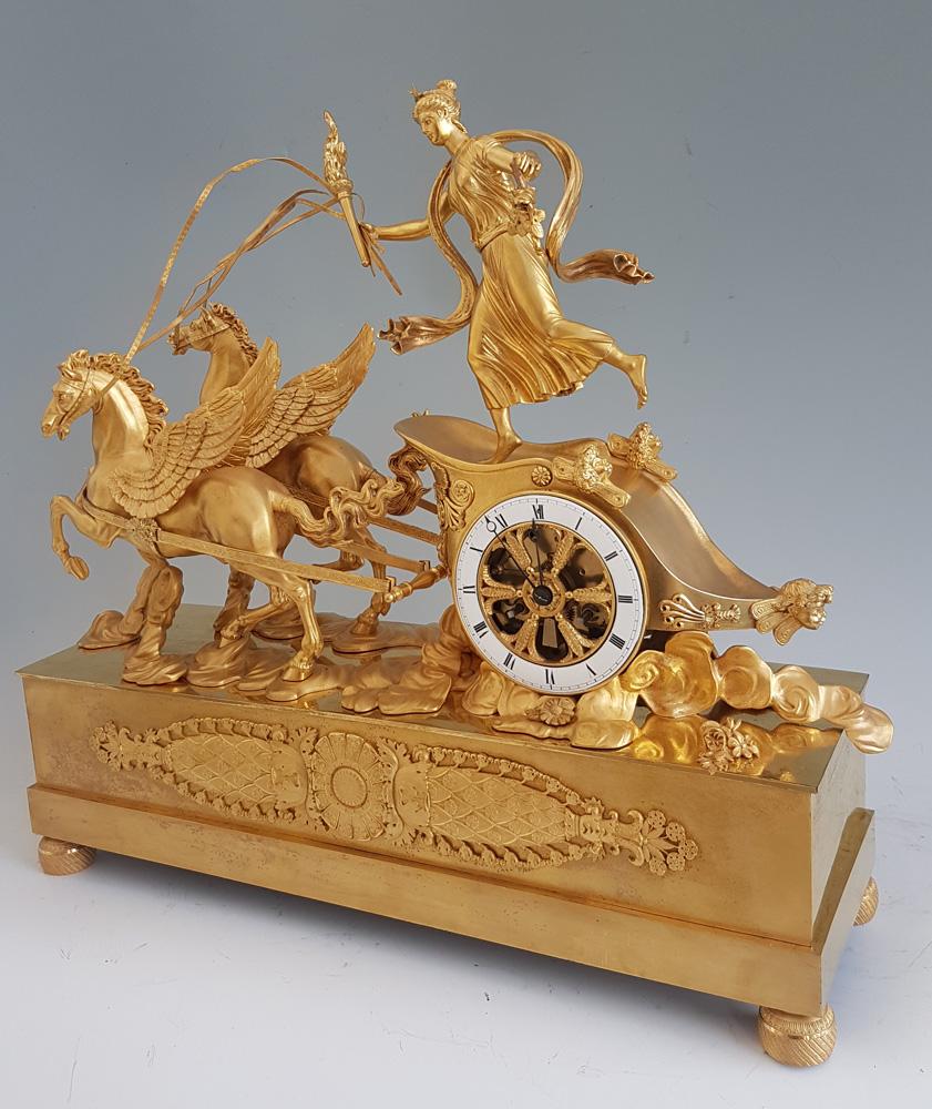 Début du XIXe siècle Pendule de cheminée Empire française en bronze doré représentant Aurore dans son char tiré par ses ailes en vente