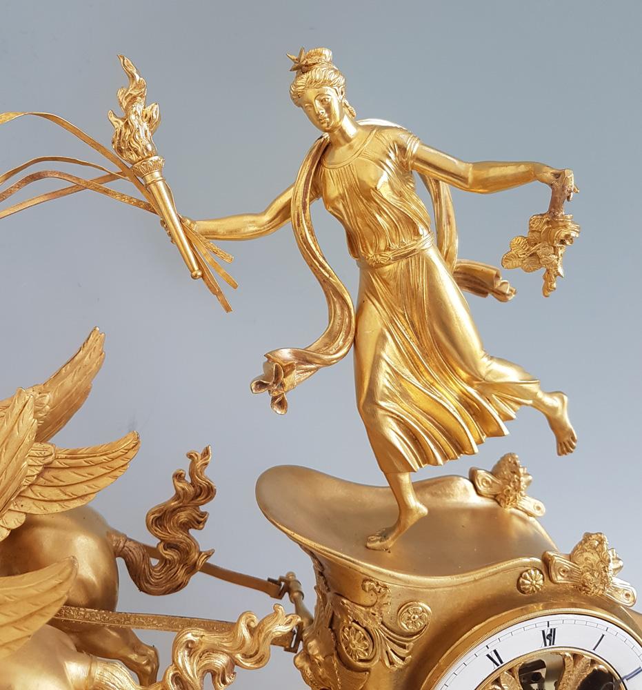 Bronze doré Pendule de cheminée Empire française en bronze doré représentant Aurore dans son char tiré par ses ailes en vente