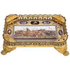 Tintenfass aus der Zeit des französischen Kaiserreichs mit vergoldeten Metallverzierungen und einer Porzellanplakette mit einem Mosaik von Alexander
