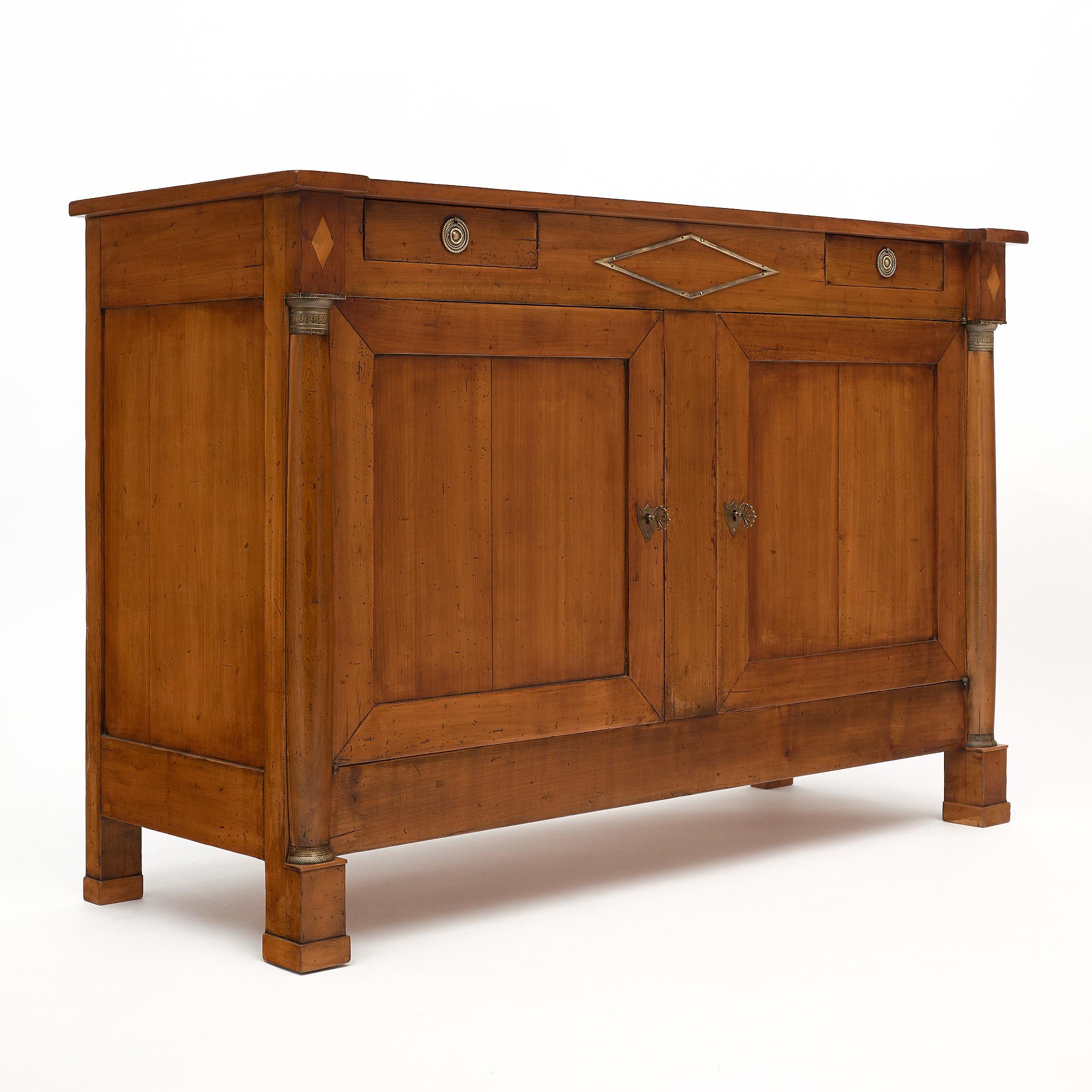 Buffet from France made of solid walnut with bronze detailing adorning the detached columns and two dovetailed drawers. There are also two doors that open to interior shelving.
