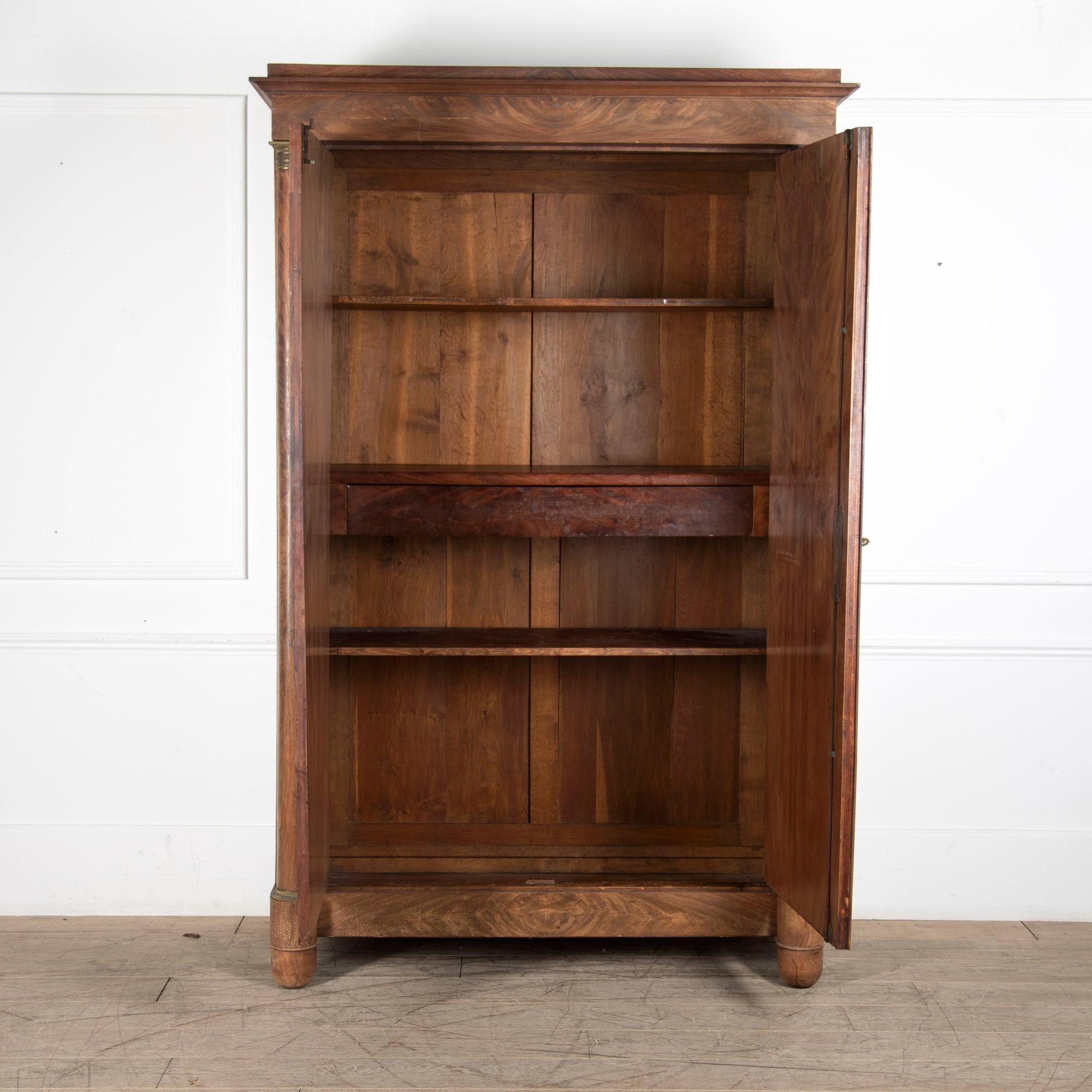19th Century French Empire period armoire.
With stunning book matched walnut veneer to the two long doors flanked by two columns.
Original restrained brass detailing.
A handsome piece that has great restraint and simplicity. It would make a