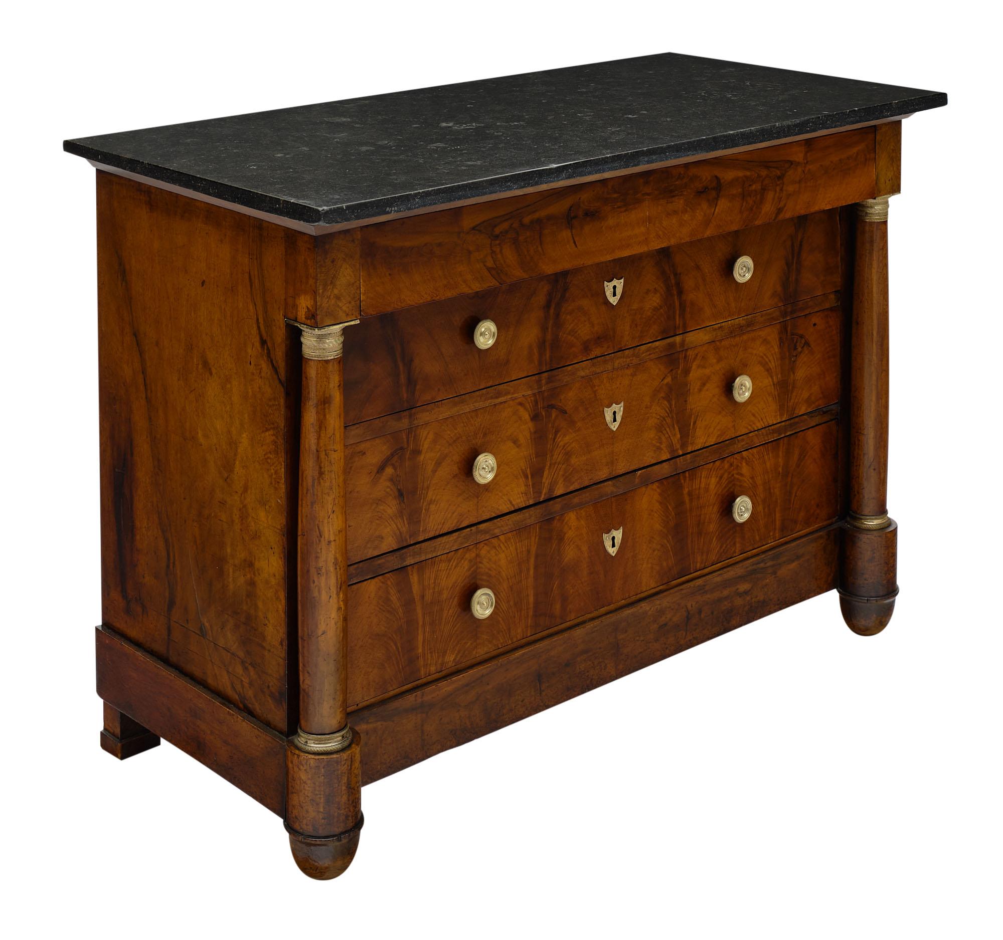 Chest / commode from the French Empire period made of solid walnut and burled walnut veneer. This piece has lovely detached columns with finely cast bronze hardware. It features an intact black marble slab top and four dovetailed drawers.