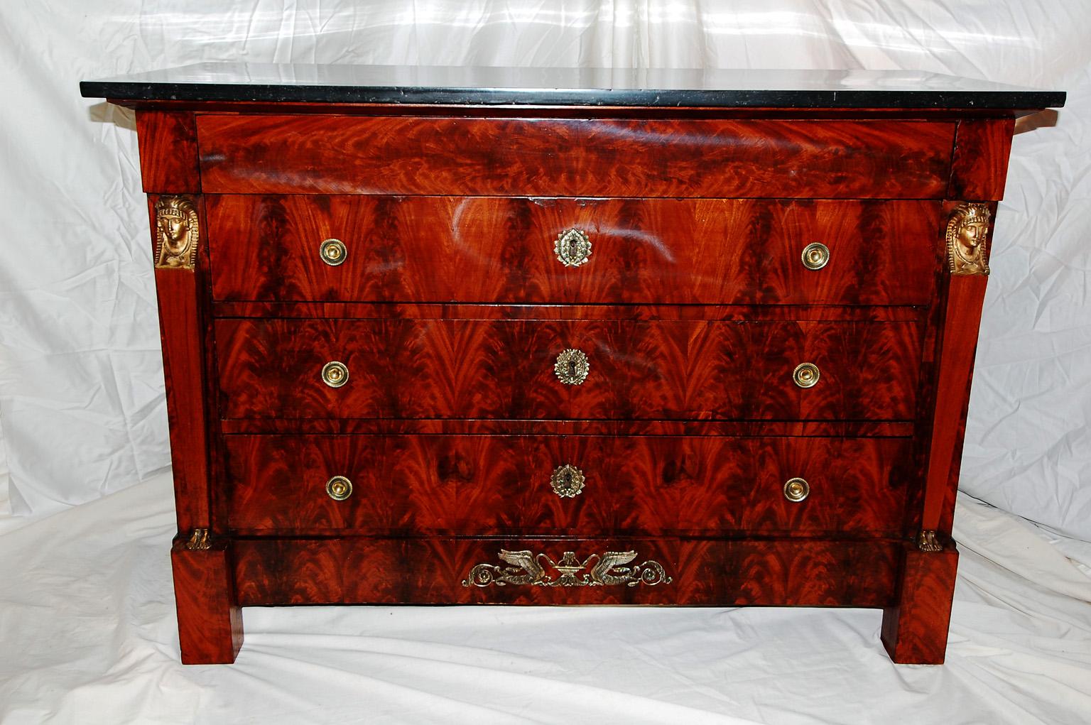 French Empire period commode (chest) in matched flame grain mahogany, Egyptian caryatid columns with ormolu head and feet, swan ormolu mount to lower frieze, laurel leaf escutcheons and round pulls. This handsome chest retains its original separate