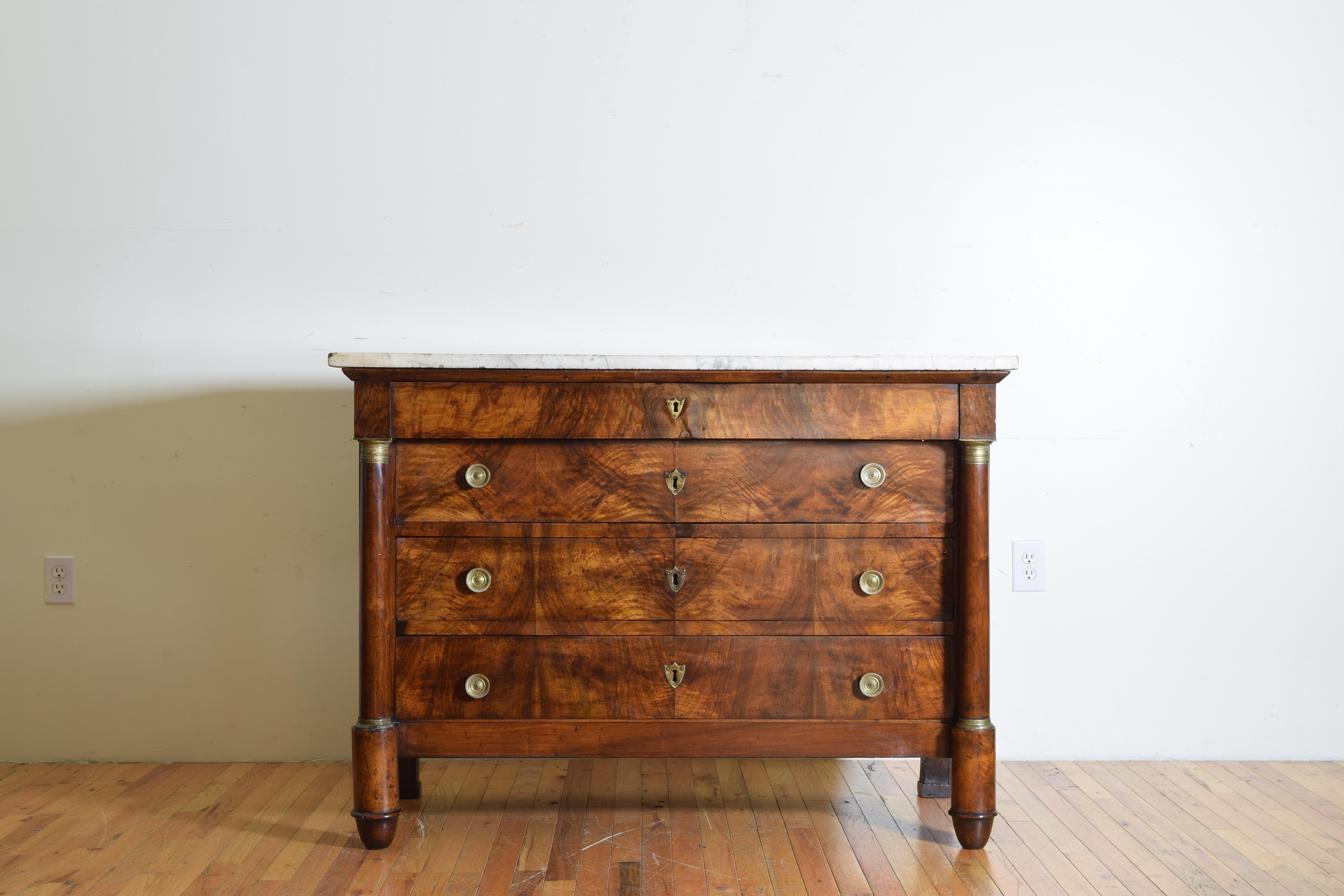 Having a white and grey veined rectangular top above a conforming case in walnut veneer, the unmarked upper drawer with hand hold pulls underneath above three large drawers flanked by columns with brass capitals, raised on rounded feet.