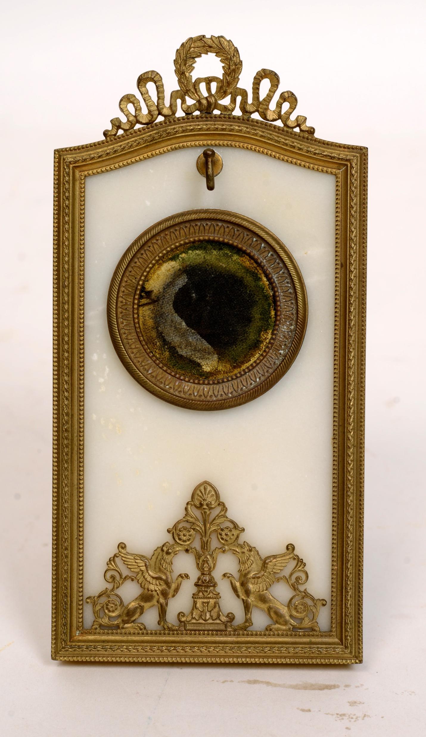 French Empire period watch holder, circa 1800. Marble and gilt bronze, with gilt bronze griffons, topped with gilt bronze laurel leaf and ribbon. The watch is supported and hangs in a gilt bronze surrounded circle. Griffons were a legendary creature