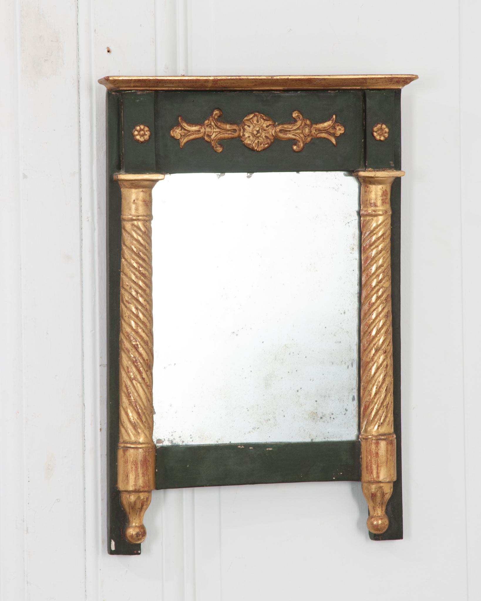 Ce petit trumeau d'époque Empire a été fabriqué à la main en France vers 1830. Peint d'un vert profond et accentué de rosettes dorées et de formes de colonnes torsadées flanquant la plaque de miroir originale. Quelques rousseurs sont visibles, sans