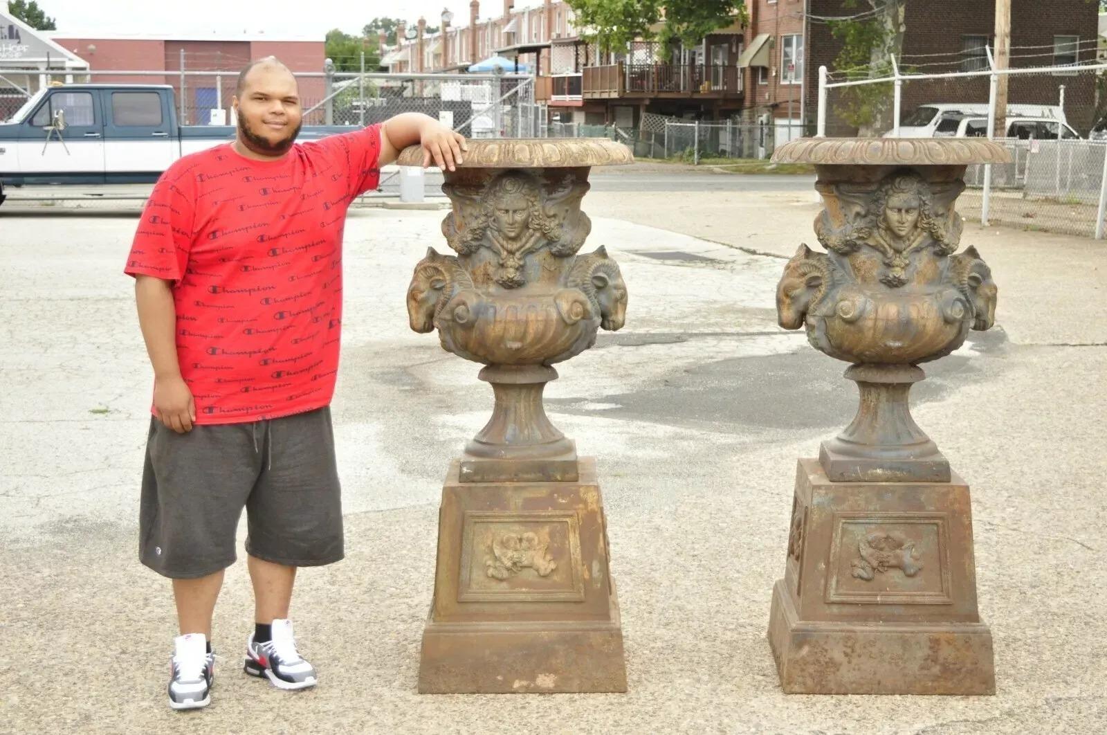 Fioriere da giardino grandi in ghisa a testa di ariete in stile impero francese reggenza - una coppia. L'articolo è caratterizzato da arieti e volti di fanciulle, costruzione in ghisa pesante, grande forma imponente, putti che si baciano sulle basi
