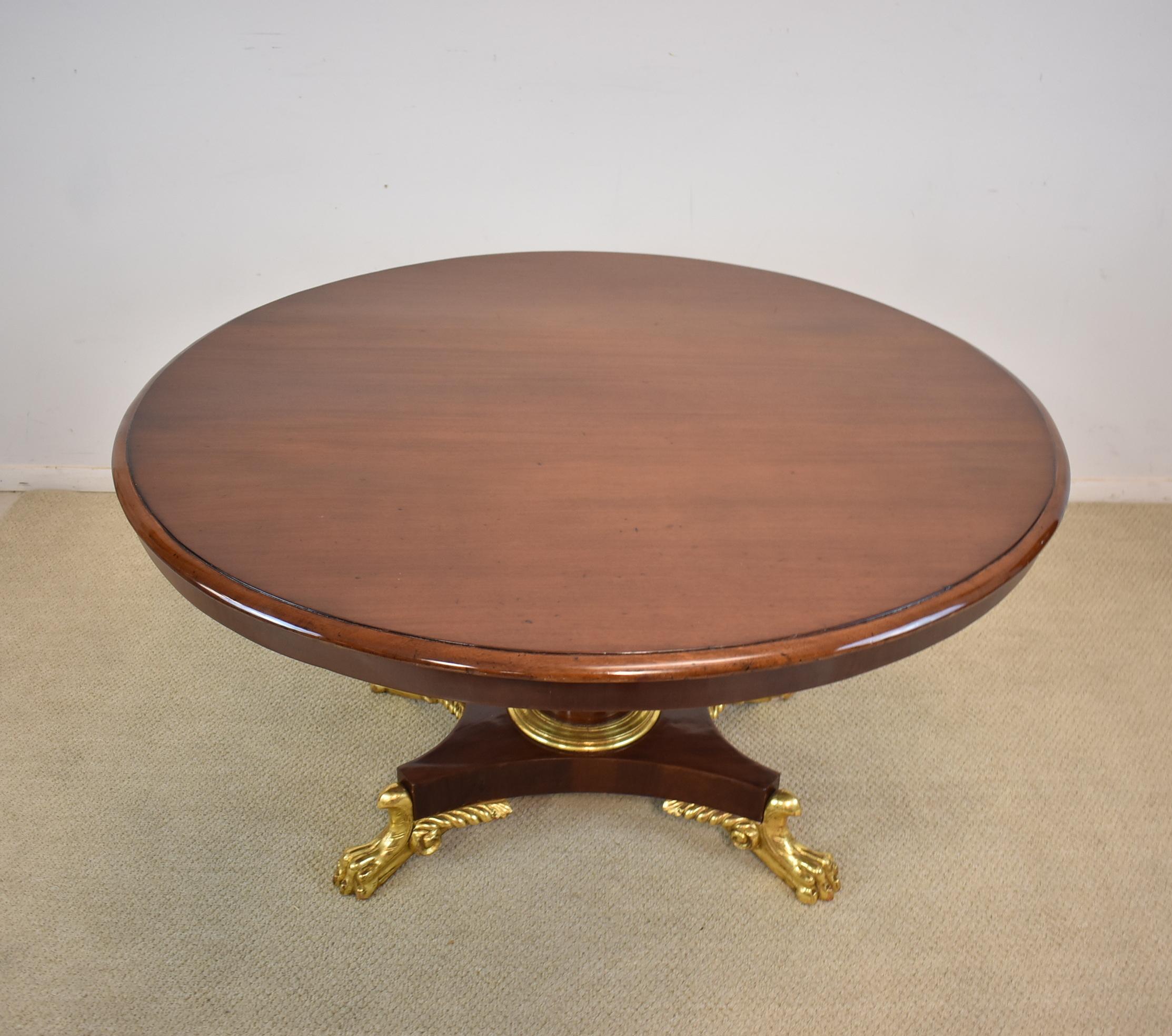 A stunning round center table from the late 1800s. This beautiful mahogany table features a high glossy finish and a pedestal base with gold gilt paw feet. The top is removable. The dimensions are 28.5