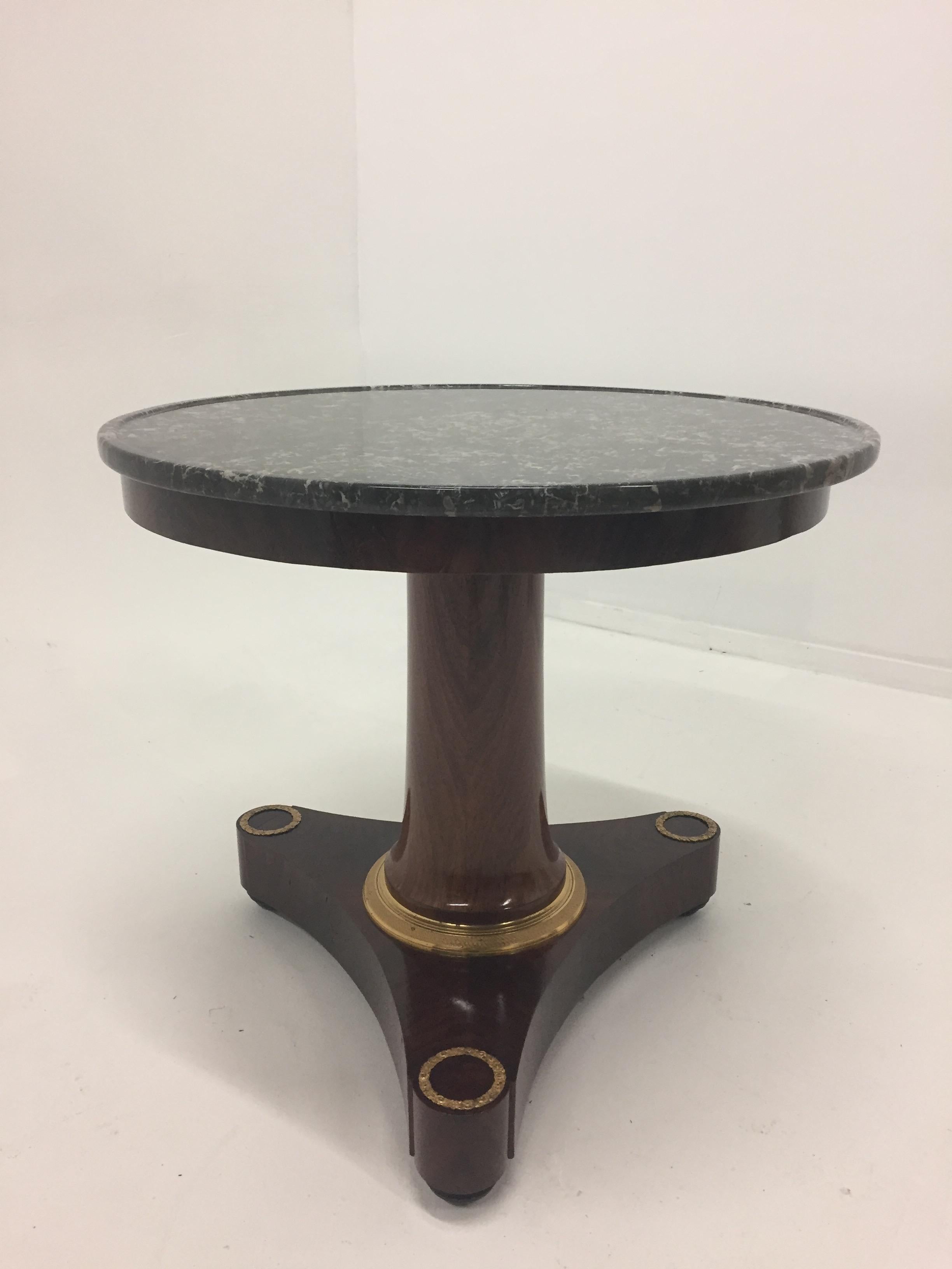 Impressively elegant and versatile round mahogany table having beautiful bronze mounts, ebonized bun feet and a handsome dark grey marble top with cream veining running through it finished with a honed edge.