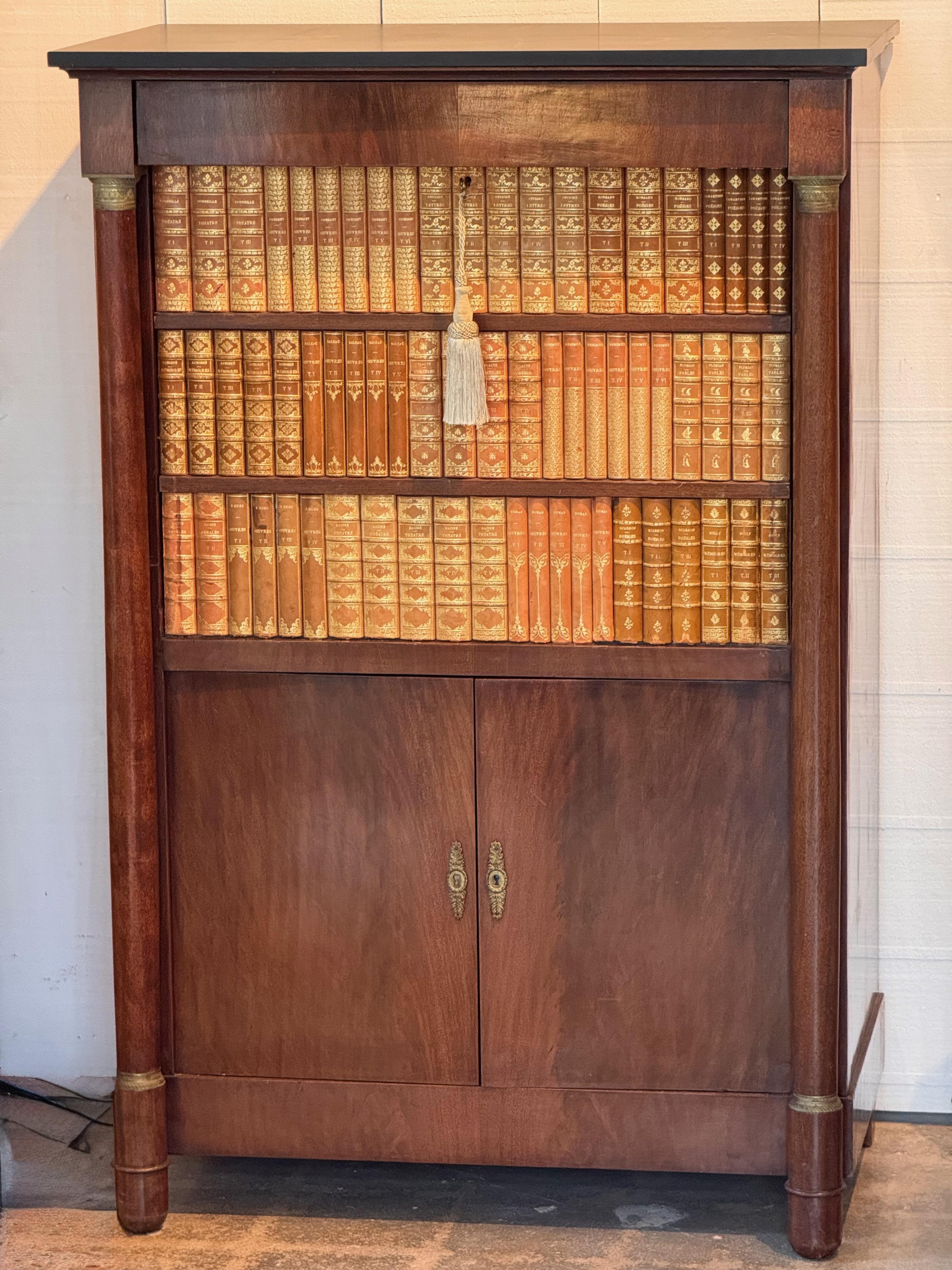 Alto secretaire à abattant in stile Impero francese con superficie di scrittura a ribalta e facciata a libro. Realizzato con una ricca impiallacciatura di mogano e impreziosito da montature in bronzo dorato e supporti laterali a colonna. L'interno