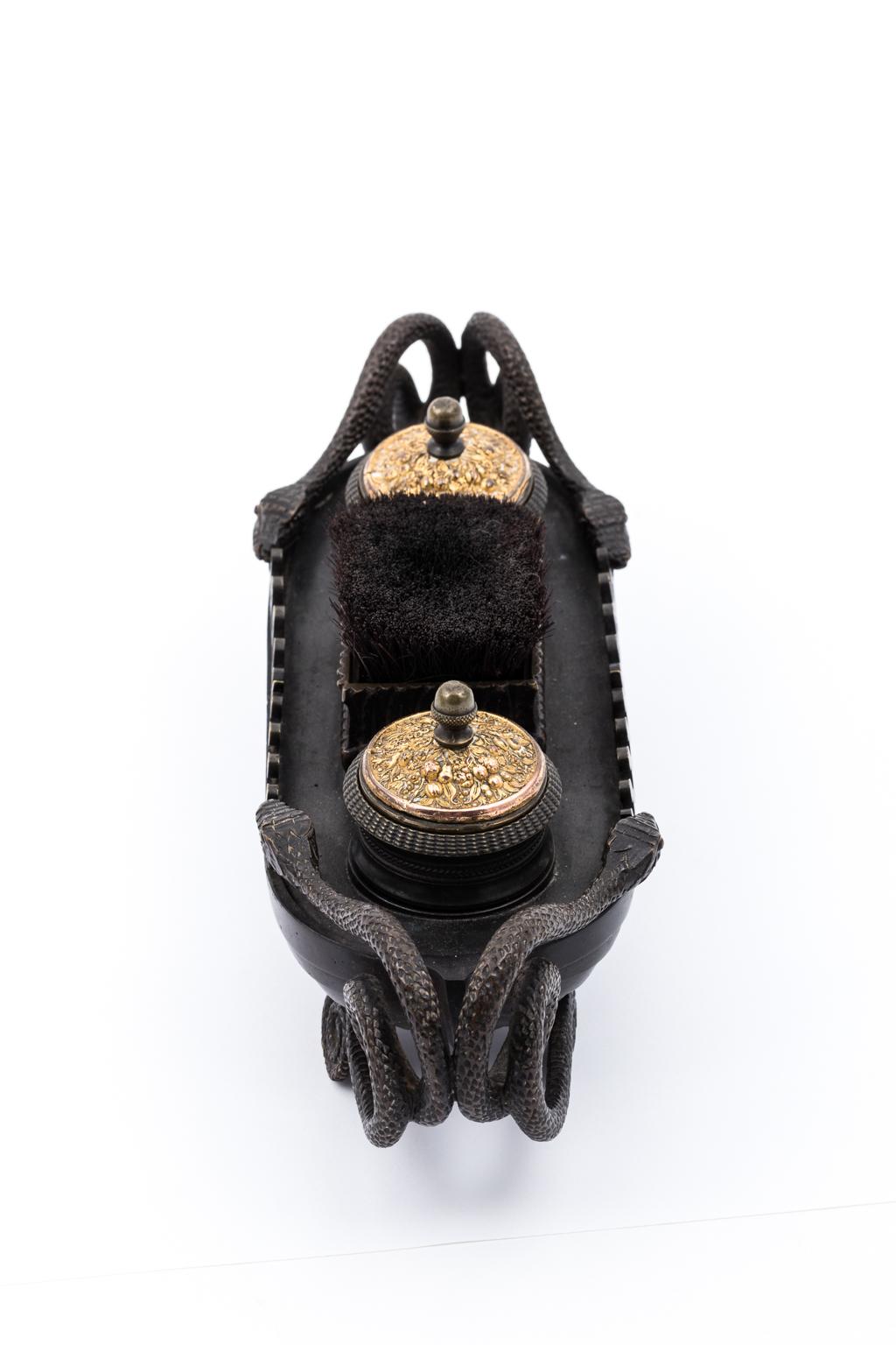Bronze inkwell stand from the Second Empire period, circa 1840-1870. Made in France, it consists of two inkwells and a center pen wipe. It also features two intertwined serpents at each end with Vitruvian scroll trim. Weight 44.99 Ounces. Please