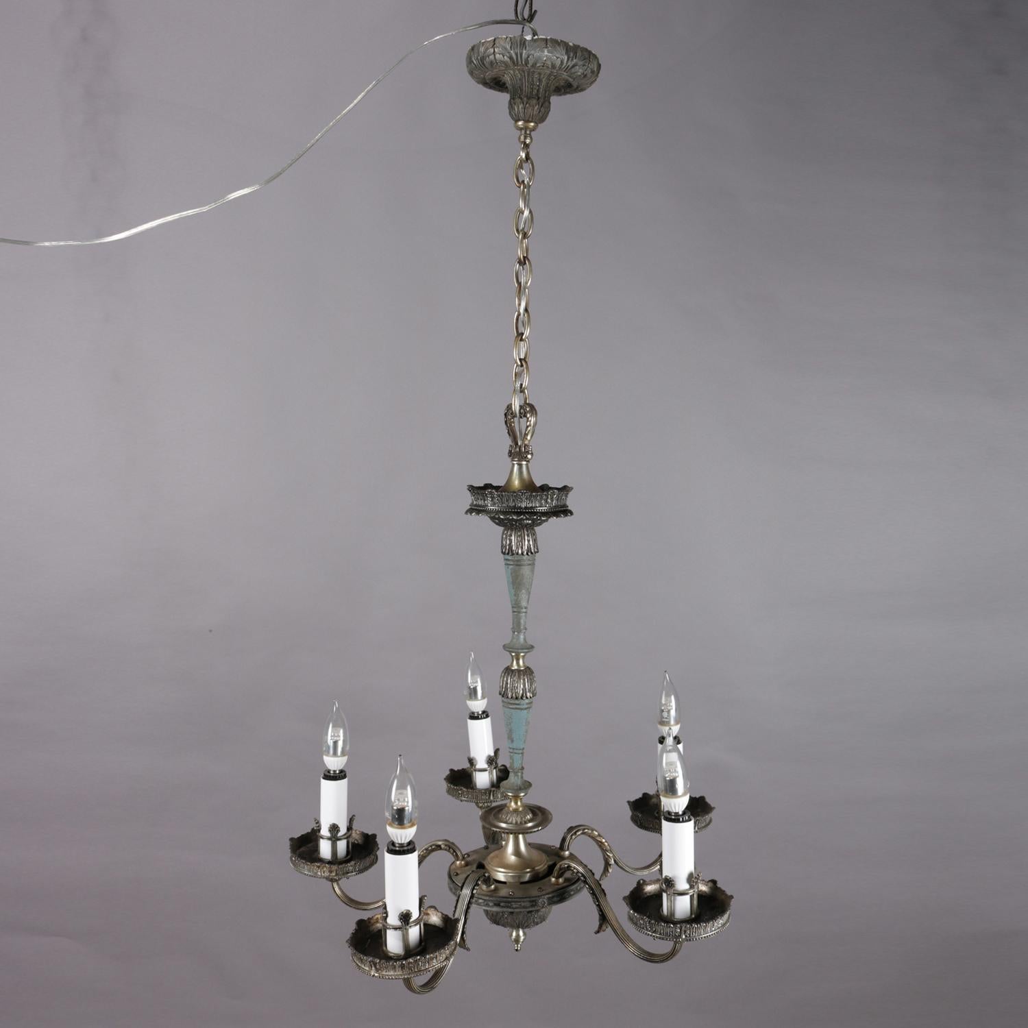 A French Empire style branch chandelier features silver gilt metal frame having five s-scroll arms terminating in oversized bobeches and candle lights, cast foliate acanthus leaves throughout, receptors for hanging prisms if desired, professionally