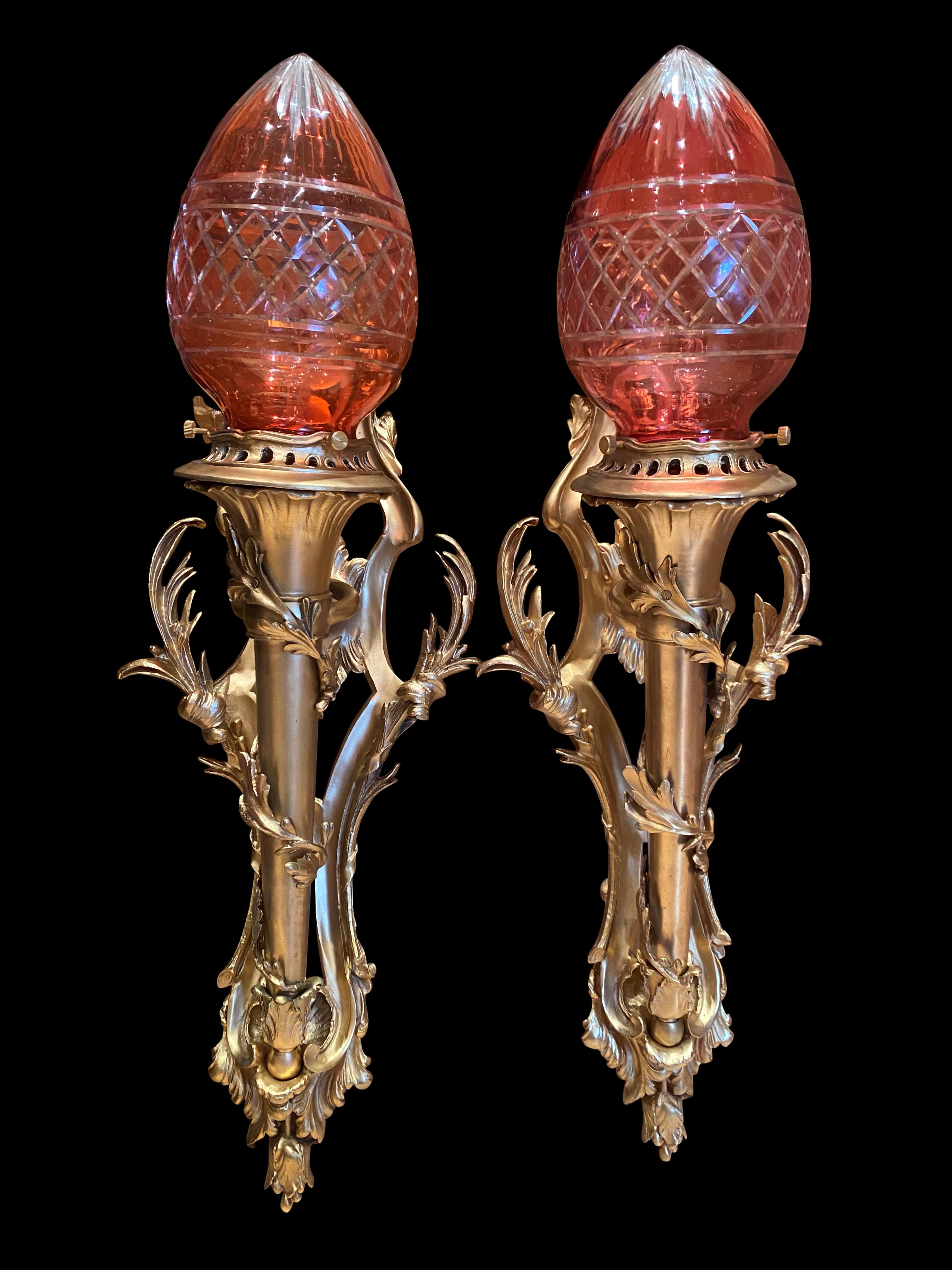 A pair of French Empire Statue of Liberty wall sconces, 20th century. Beautifully intwined foliage running up central stem. Highly decorative with cut crystal ruby colored shades.