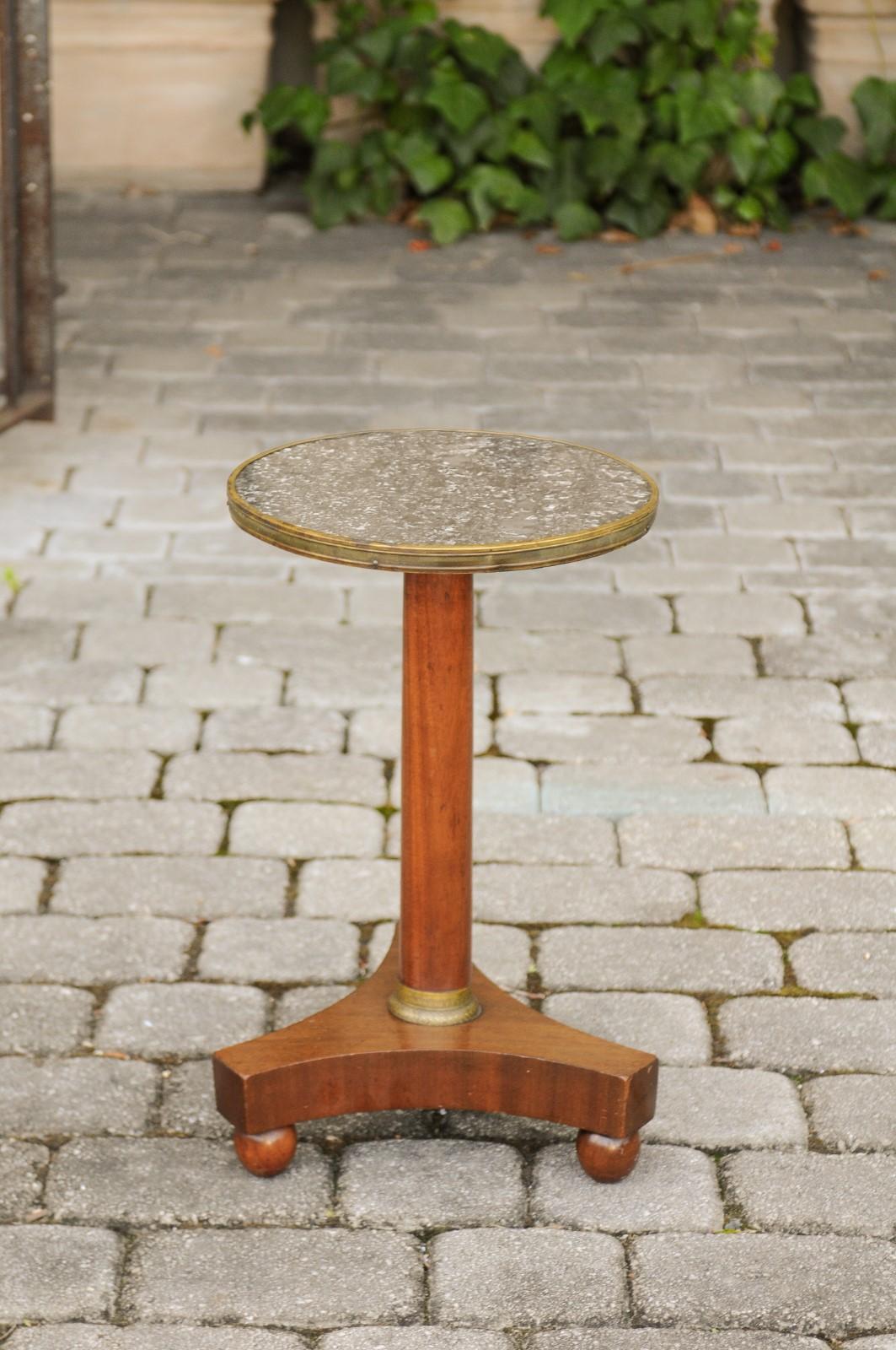 A French Empire style walnut gueridon side table from the late 19th century, with marble top and bronze accents. Born in France during the third quarter of the 19th century, this elegant gueridon features a circular grey marble top with brass trim,