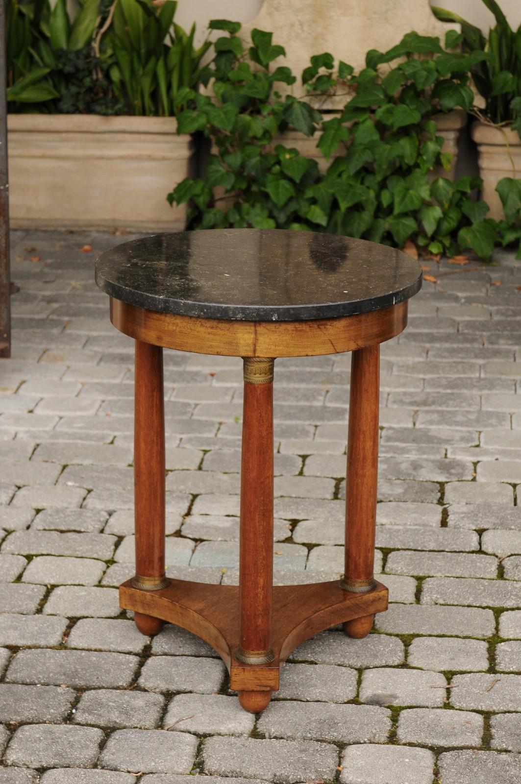 A French Empire style walnut guéridon side table from the late 19th century, with black marble top and bronze mounts. Born in France during the third quarter of the 19th century, this handsome guéridon features a circular black marble top, sitting