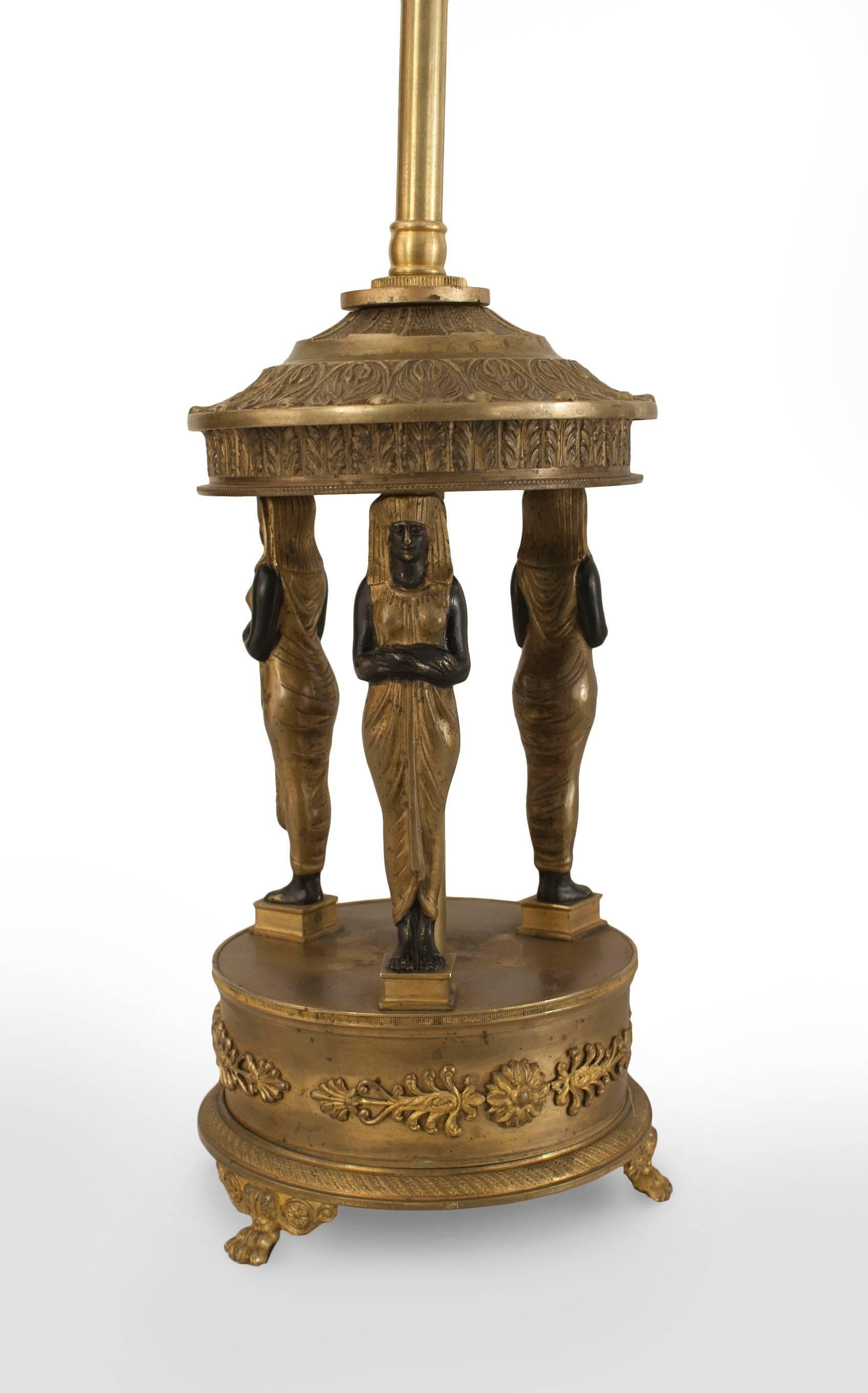 Lampe en bronze de style Empire français (19e siècle) avec 3 figures égyptiennes ébonisées et dorées reposant sur une base ronde.
