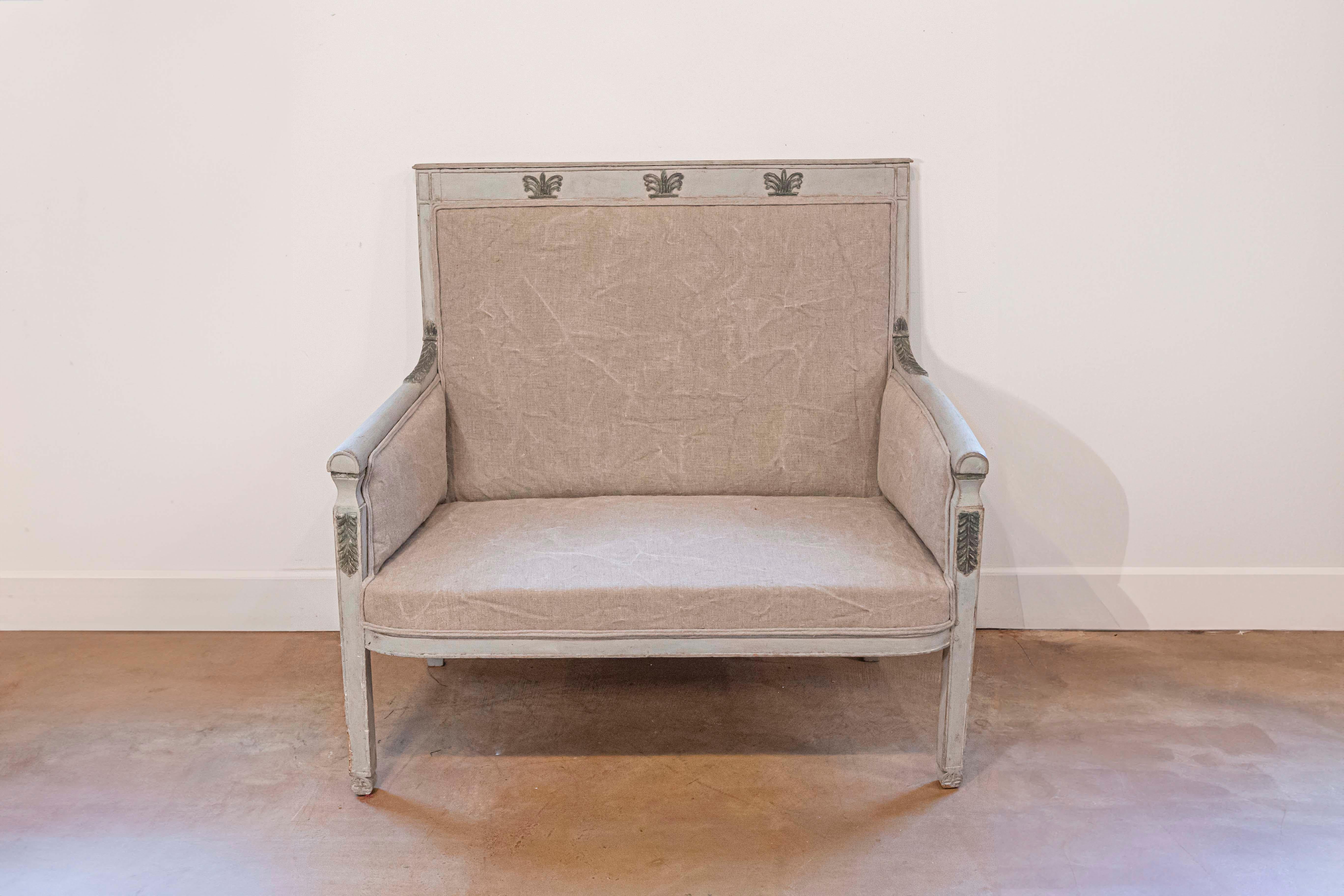 A French Empire style painted wood marquise chair from the 19th century, with carved palmettes. Born in France during the politically dynamic 19th century, this French Empire style marquise features a rectangular upholstered back, accented with
