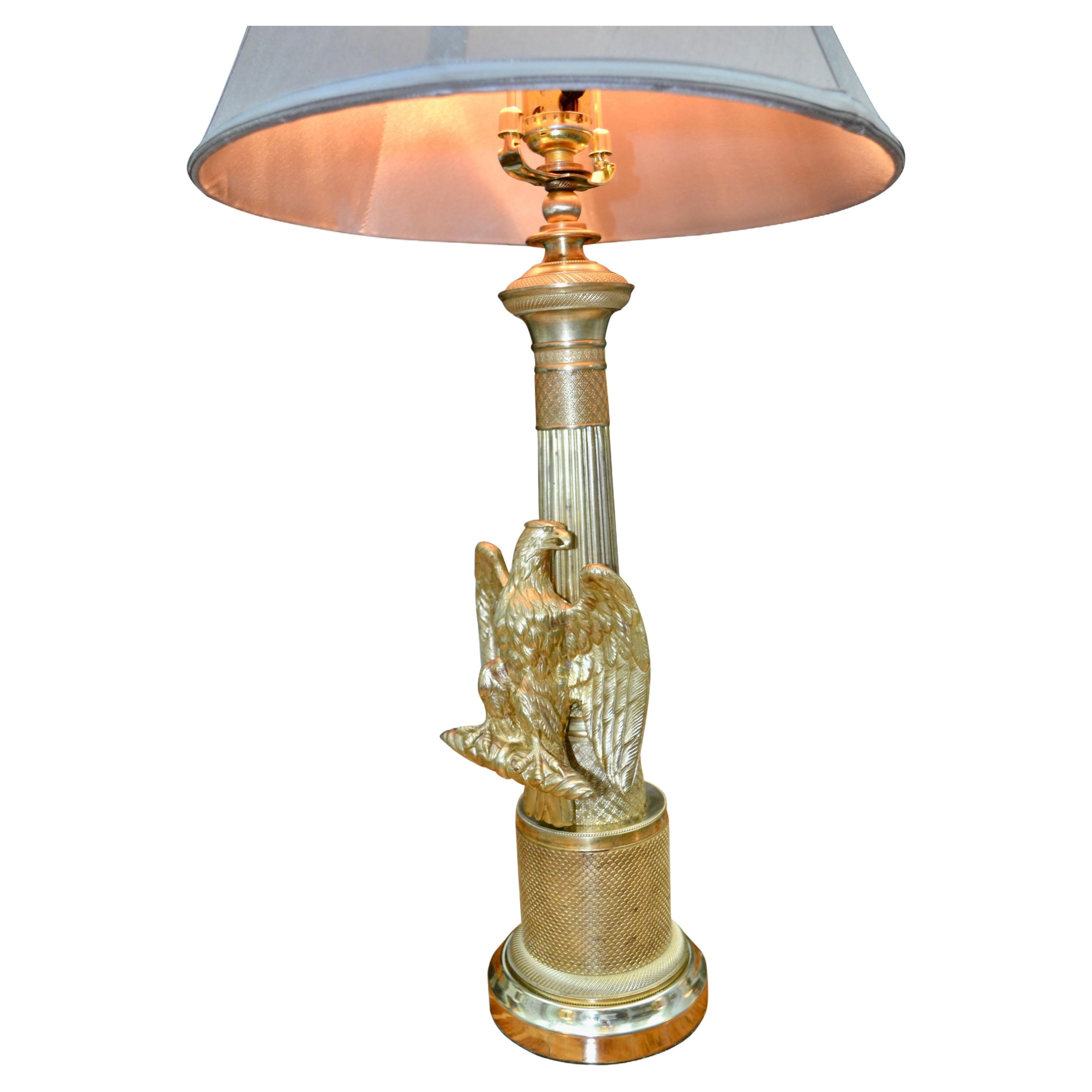 A  highly decorative French empire style lamp likely made in the early 20thC. The polished brass column was likely the stem of a candelabra which was later embellished with an eagle standing on a fascia with his wings outstretched. The brass has