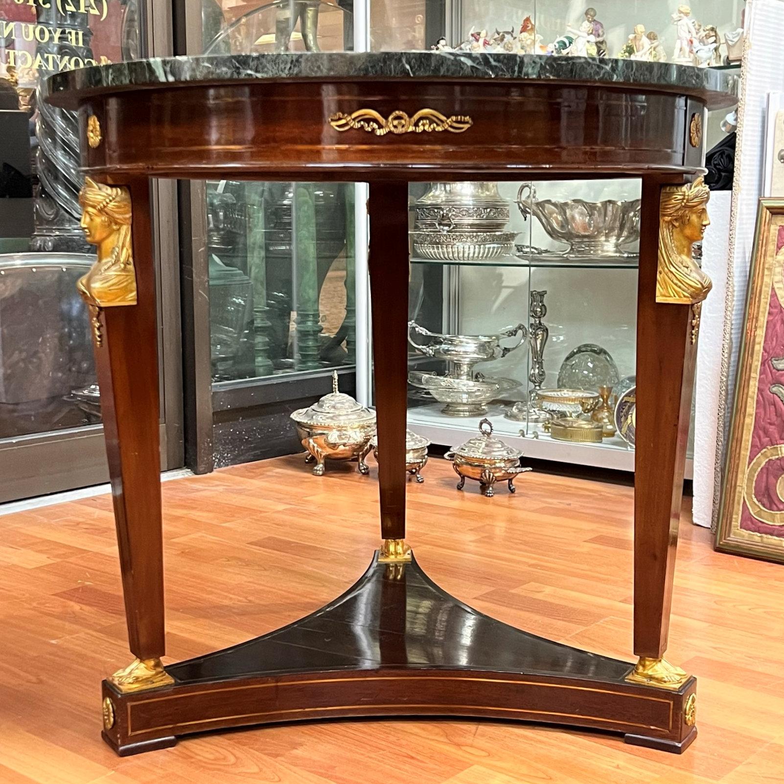 Our gueridon table in the Empire style, circa 1880s with mahogany veneer features legs in pilaster form surmounted by female Egyptian figures and feet in gilt bronze, and fruitwood bands decorating the stretcher and legs. Apparently unsigned.