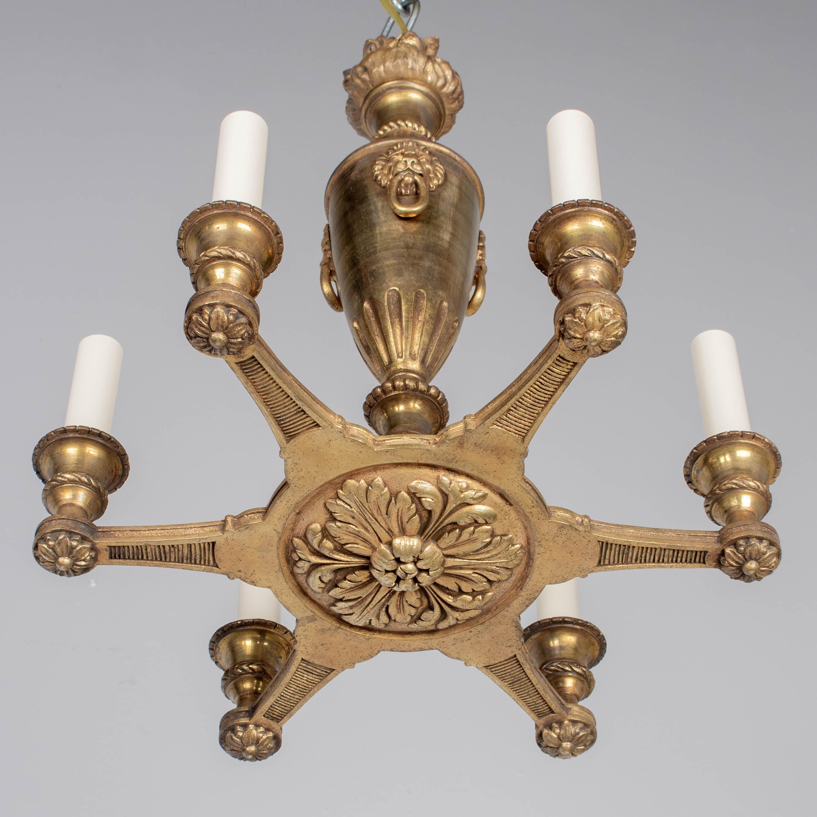 Araña de seis luces de bronce fundido de estilo Imperio francés. Forma de antorcha con llama en la parte superior, decorada con tres cabezas de lomo. Seis brazos con medallones foliados debajo. Recableado y en condiciones de funcionamiento. Enchufes