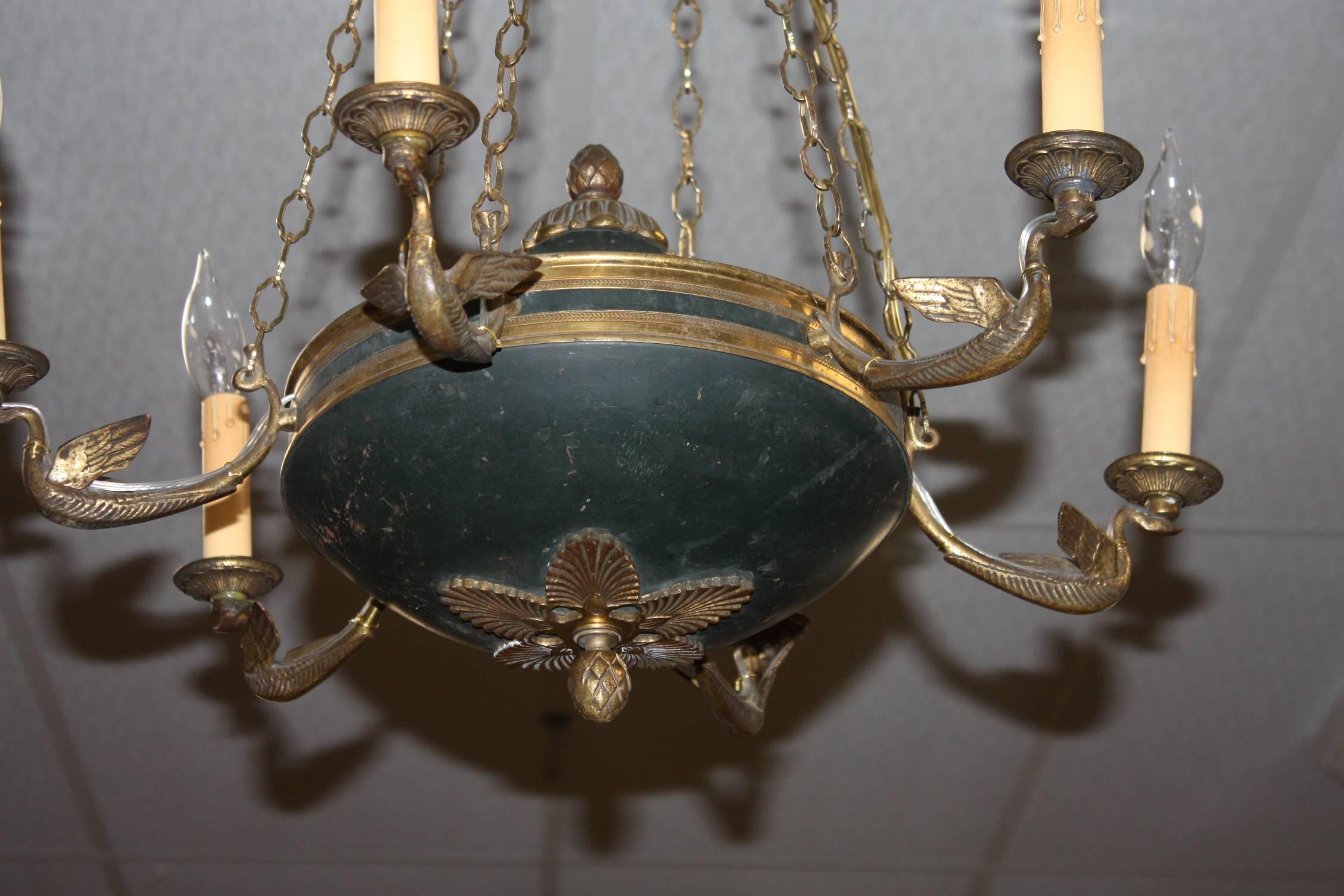 French Empire style patinated and gilt metal six-arm chandelier of oil lamp form with flambeau centre. The corona is of patinated bronze with ormolu anthemia decorated shapes above a laurel border.
