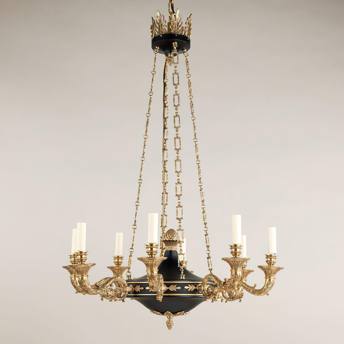 French Empire style eight-light chandelier, with intricate brass casting that, contrasts with the black to create a striking effect. The fine detail of the chains complements the finial and decorative arms. With an ornate crown, scrolling arms, and