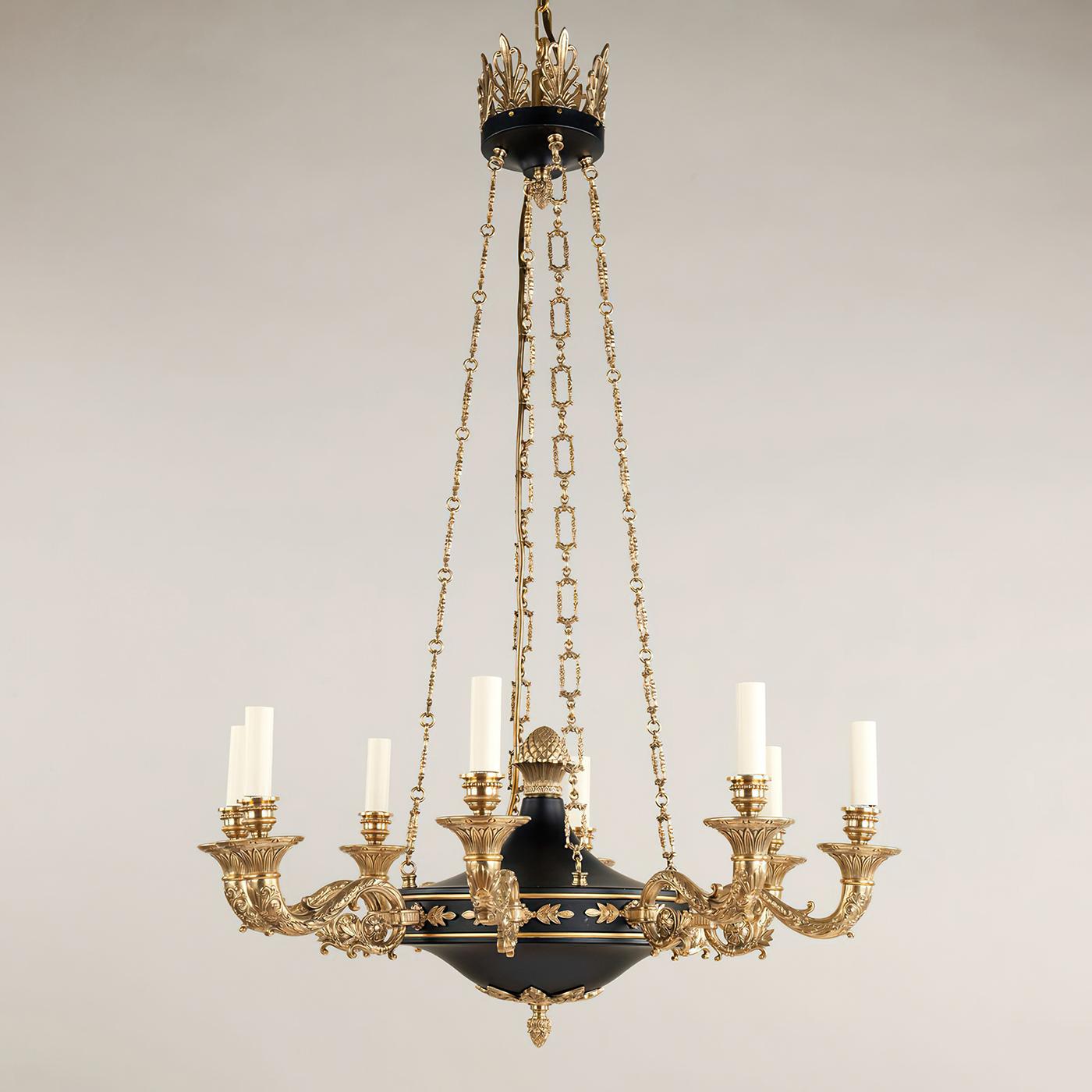 Lustre à huit lumières de style Empire français, avec des moulages complexes en laiton qui contrastent avec le noir pour créer un effet saisissant. La finesse des détails des chaînes complète le fleuron et les bras décoratifs. Avec une couronne