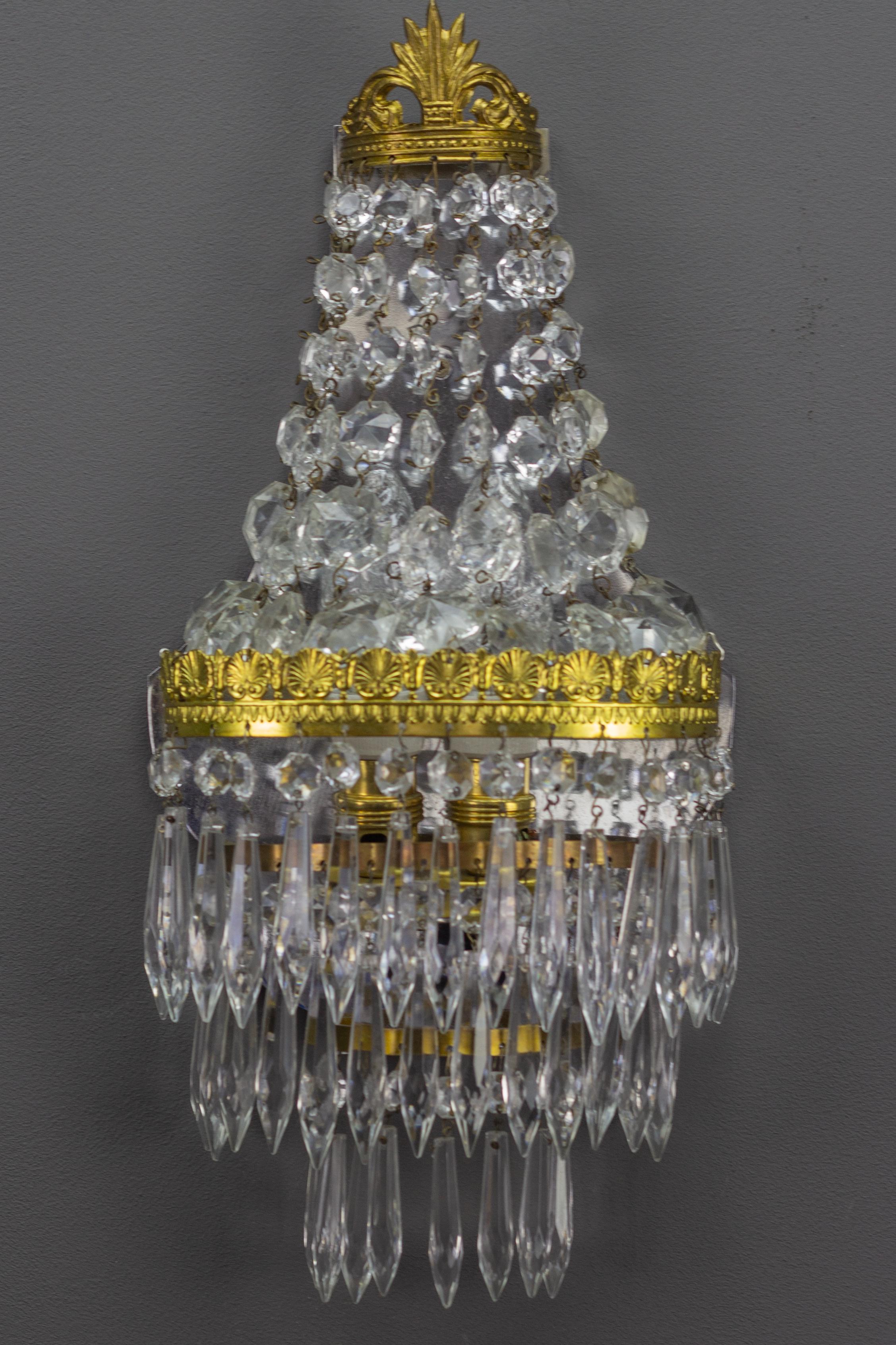Diese bezaubernde Leuchte im Empire-Stil hat einen Messingrahmen, der auf der oberen Ebene mit Kristallglasperlen und auf der unteren Ebene mit drei Reihen von Kristallglasanhängern versehen ist.
Zwei Innenleuchten mit Fassungen für Glühbirnen der