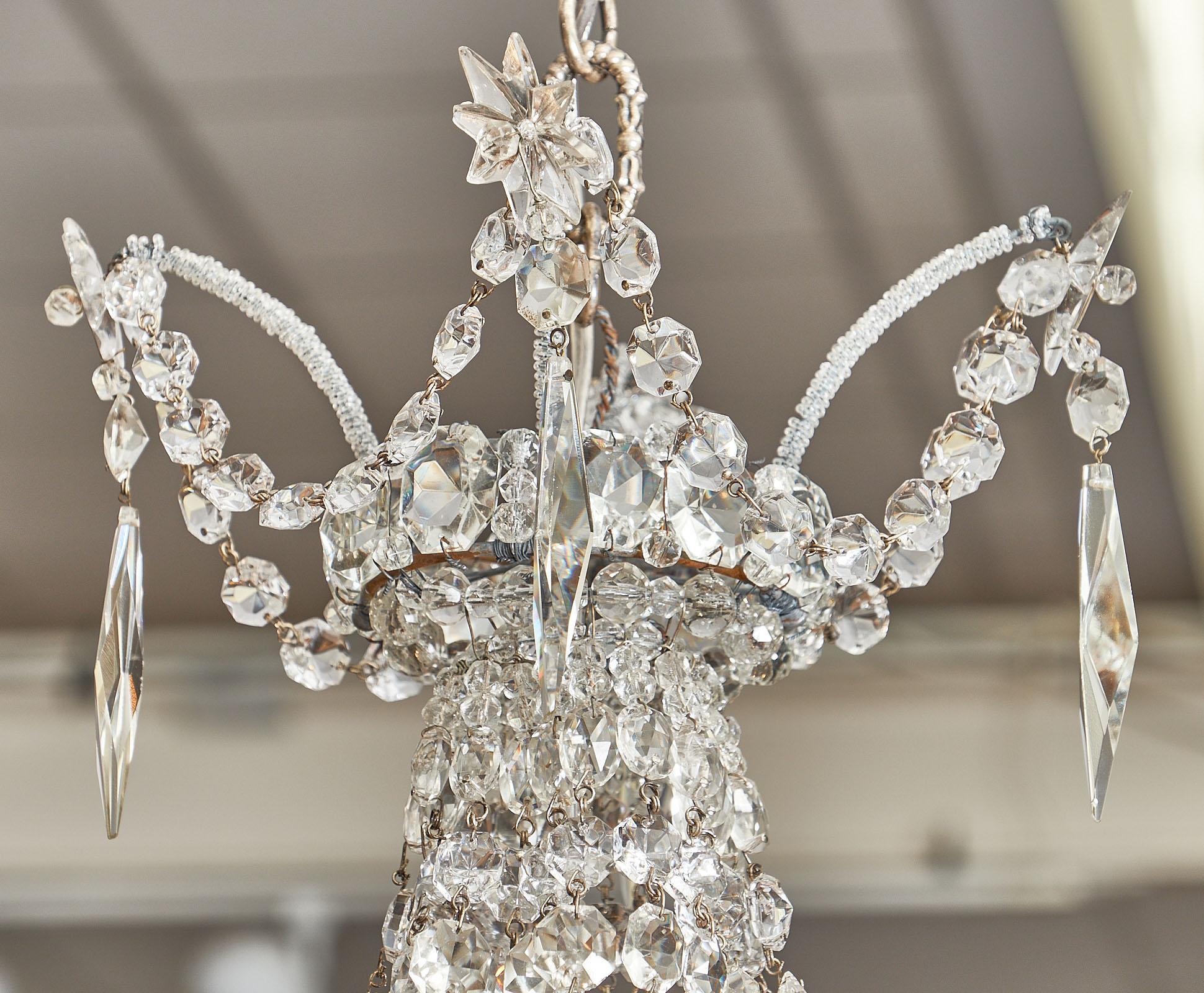 Empire Style French crystal chandelier with four bobeche and one central candelabra light within the crystals. We love the glamour of this piece purchased from Nice, France. There is also a sliver plated canopy. This vintage chandelier has been