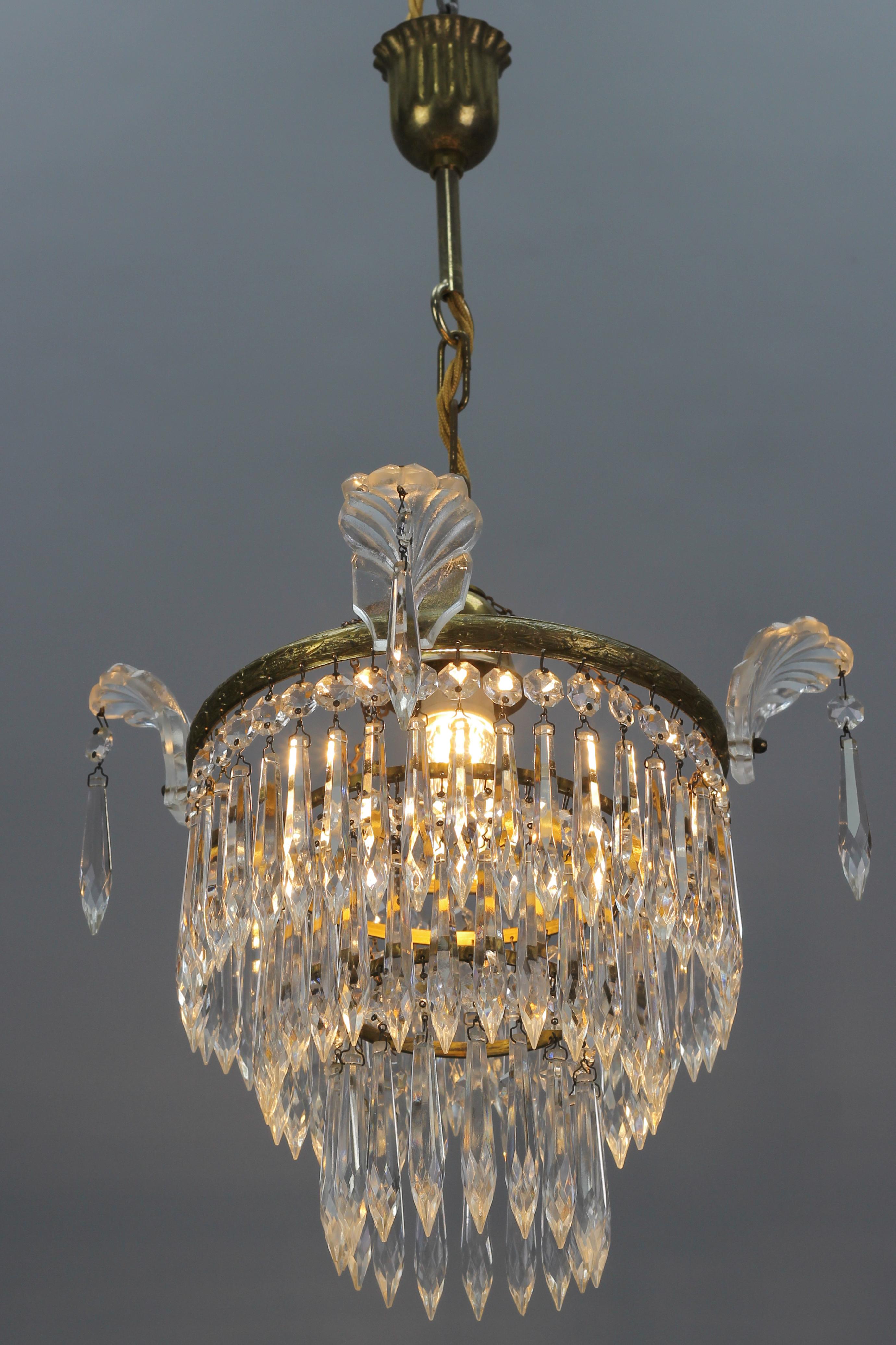 French Empire style crystal glass and brass three-tired chandelier, the 1930s.
Charming and compact French Empire-style crystal glass and brass chandelier from the 1930s. This lovely piece has an ornate bronze frame hung with beads and prisms of