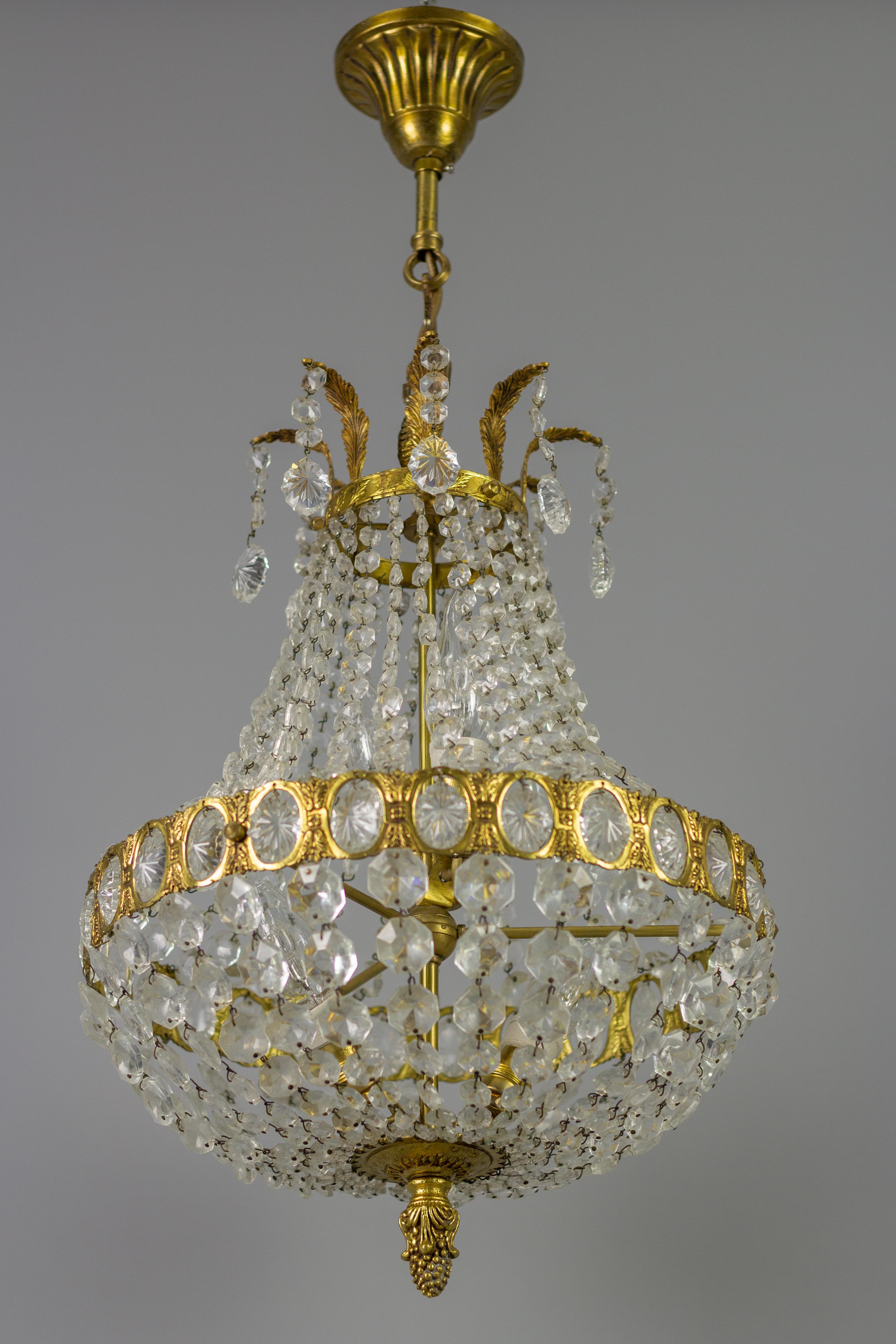 French Empire-style four-light crystal glass, brass, and bronze basket-shaped chandelier from the 1950s. This beautiful piece has decorative details made of bronze and a brass frame hung with chains of crystal glass beads forming a basket shape and