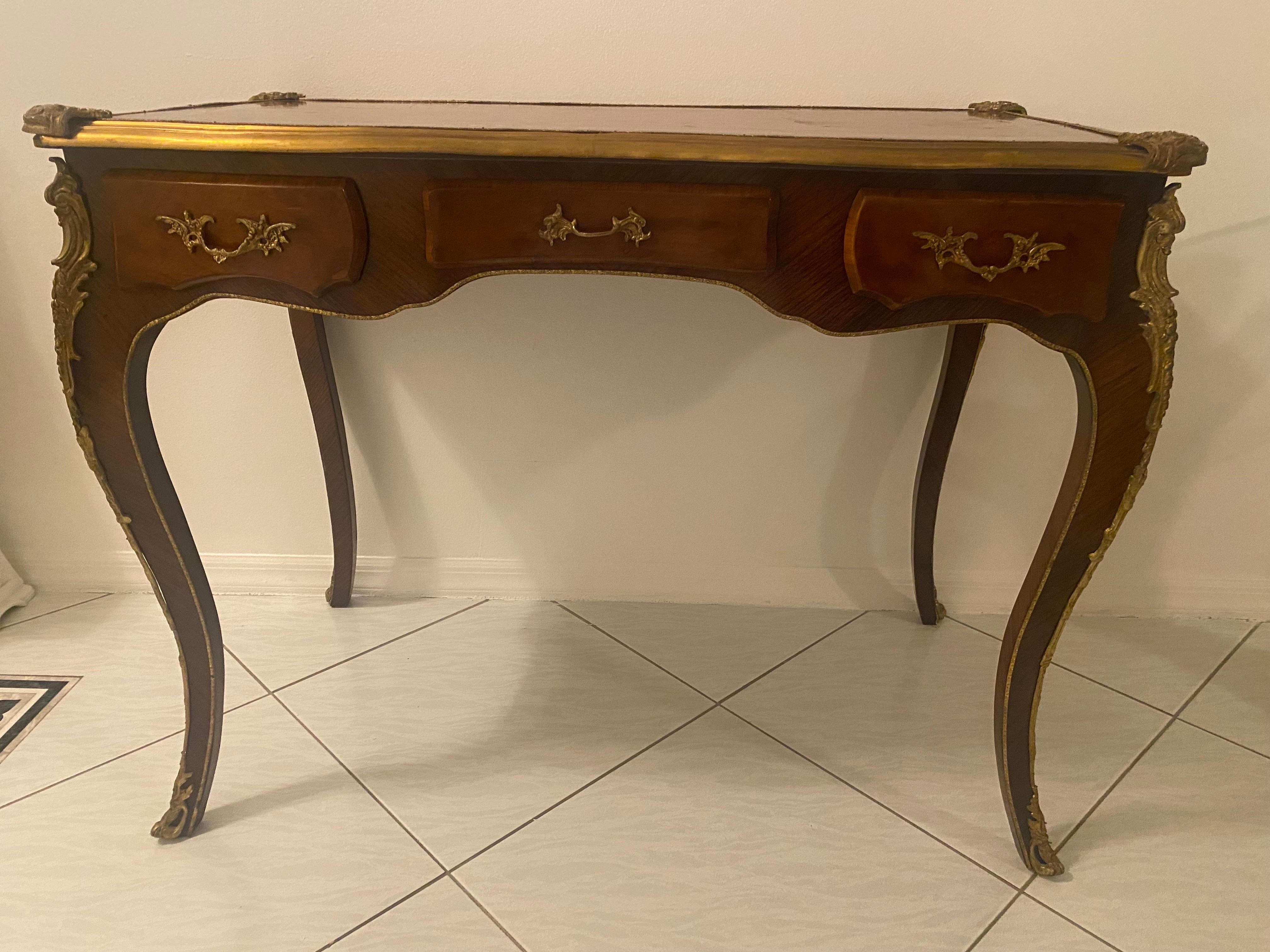 A perfect example of the Bureau Plat.

French Empire style desk with wood marquetry and gilt metal mounts at all angles. This piece features three working drawers on the front with three faux drawers on the back. The superb gilt metal hardware is on