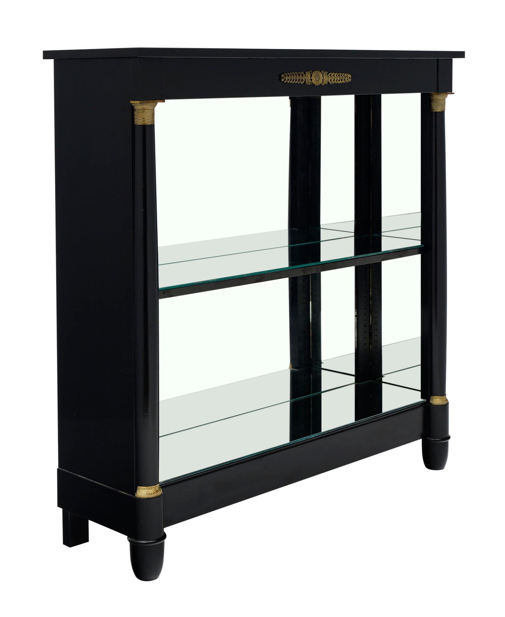 French Empire style ebonized bookcase made of solid mahogany. Finished a high luster French polish. This antique piece features an open center with a single shelf that can be adjusted to the desired height. We love the detached columns and beautiful