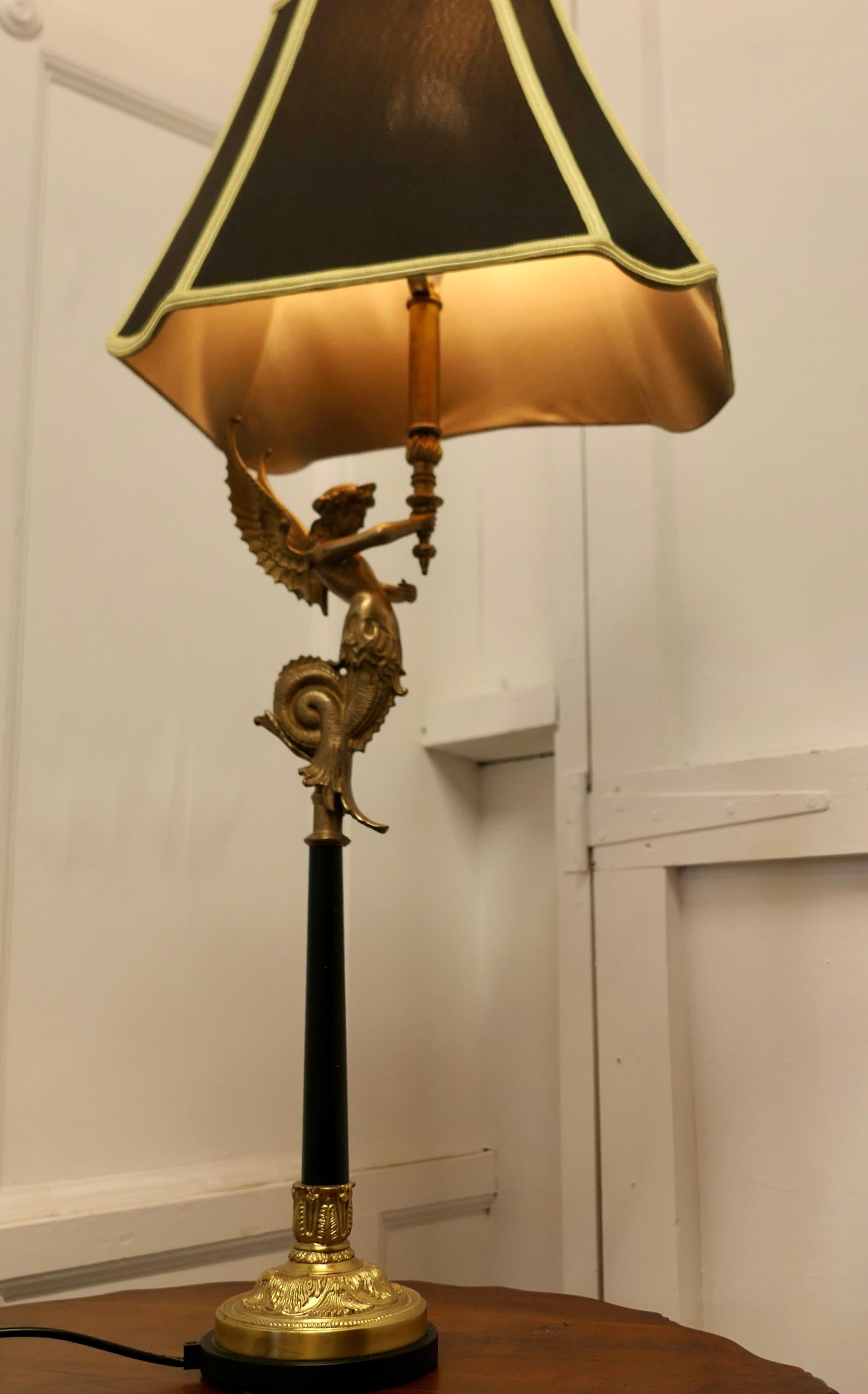 French Empire Style figural siren ormolu lamp.

A charming 3ft tall brass lamp, the silk shade is supported by the statue of a brass Siren set on a black column. 
The lamp is fully working, and the wiring is new, the lamp has its own customised