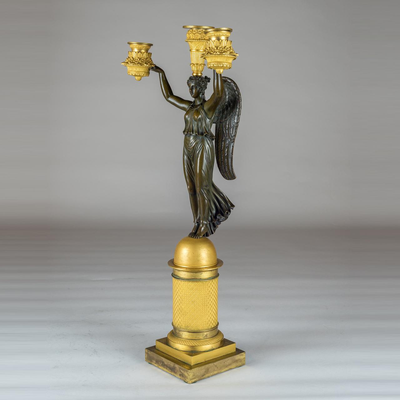 Each winged victory figure stand tipped-toed on a polished sphere. Her arms almost weightless as they comfortably lift the immense weight above her shoulders. ?

Origin: French
Date: 19th Century
Dimension: Height: 20 3/4 in.