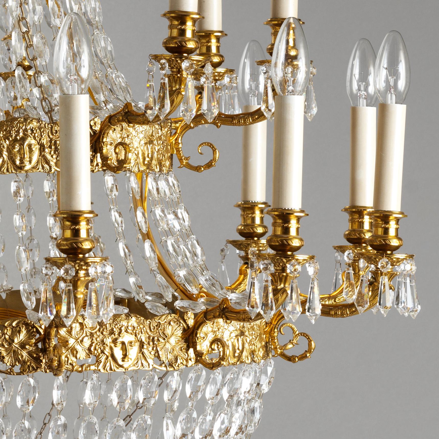 Ce lustre de style Empire français en bronze doré et cristal de Gherardo Degli Albizzi comporte vingt lumières et présente des détails artisanaux de haute qualité.
Les couronnes supérieures se caractérisent par une riche décoration végétale avec des