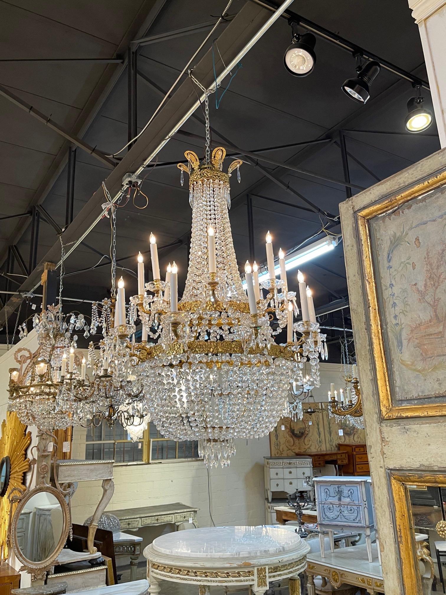 Stunning French Empire style gilt bronze and crystal chandelier with 18 lights. Gorgeous bronze details along with dazzling crystals make a huge impact. An exceptional piece!