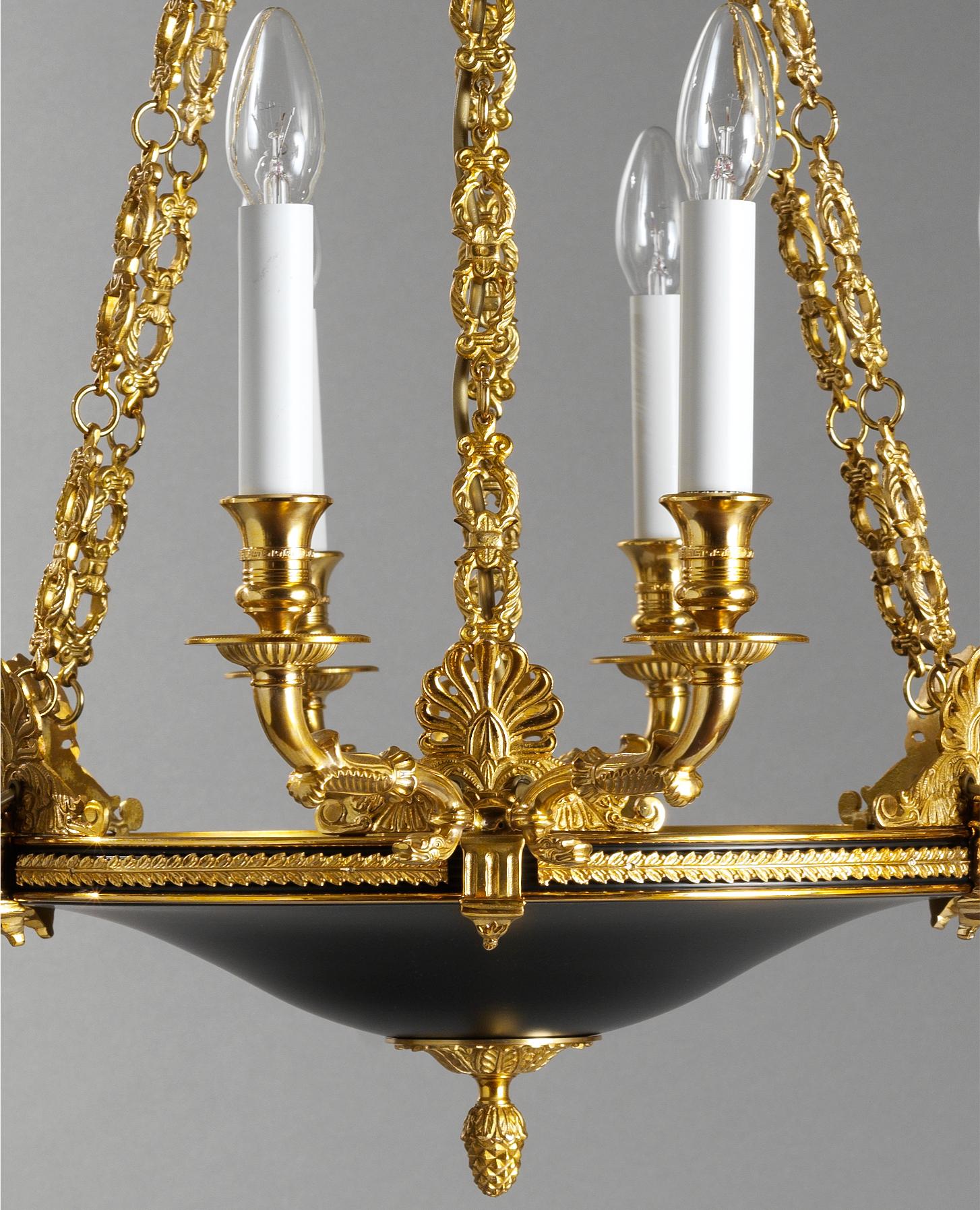 French Empire style gilt bronze and enamel chandelier by Gherardo Degli Albizzi has got  twelve lights.
This chandelier is characterized by classical plate embellished with gilt bronze acroterio and swan arms.
At the top there is a decorative crown