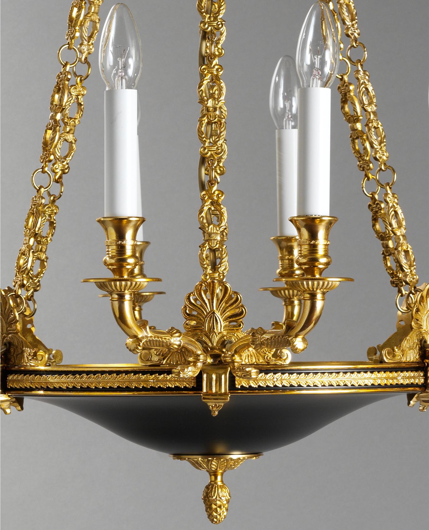 Il lampadario in bronzo dorato e smalto di Gherardo Degli Albizzi in stile Impero francese ha  dodici luci.
Questo lampadario è caratterizzato da un piatto classico impreziosito da un acroterio in bronzo dorato e da bracci a cigno.
Nella parte