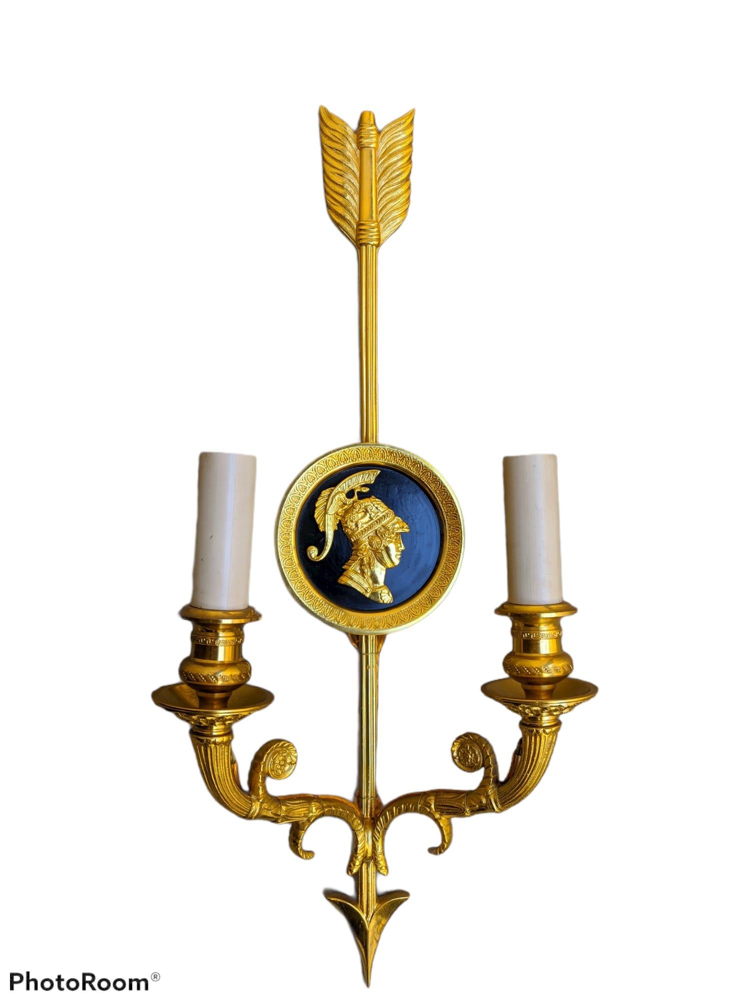 This French Empire style gilt bronze wall sconce by Gherardo Degli Albizzi features the best quality hand-chiselled details.
The backplate of this sconce features a lacquered round plate and an arrow crossing from the top to the bottom. On the