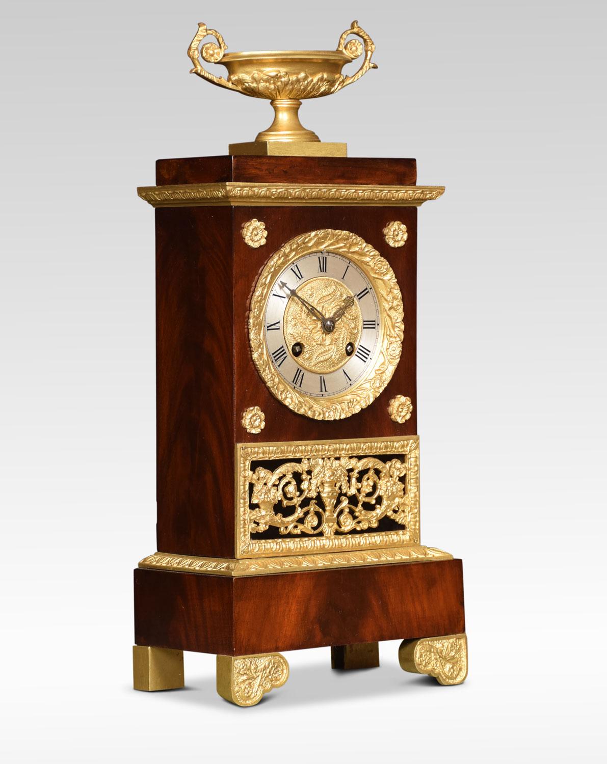 French Empire style gilt metal clock, the gilt metal mounted urn above figured mahogany case having fret cast grille below and scrolling toes. The silvered dial with Roman numerals striking on bell.
Dimensions:
Height 16 inches
Width 6.5