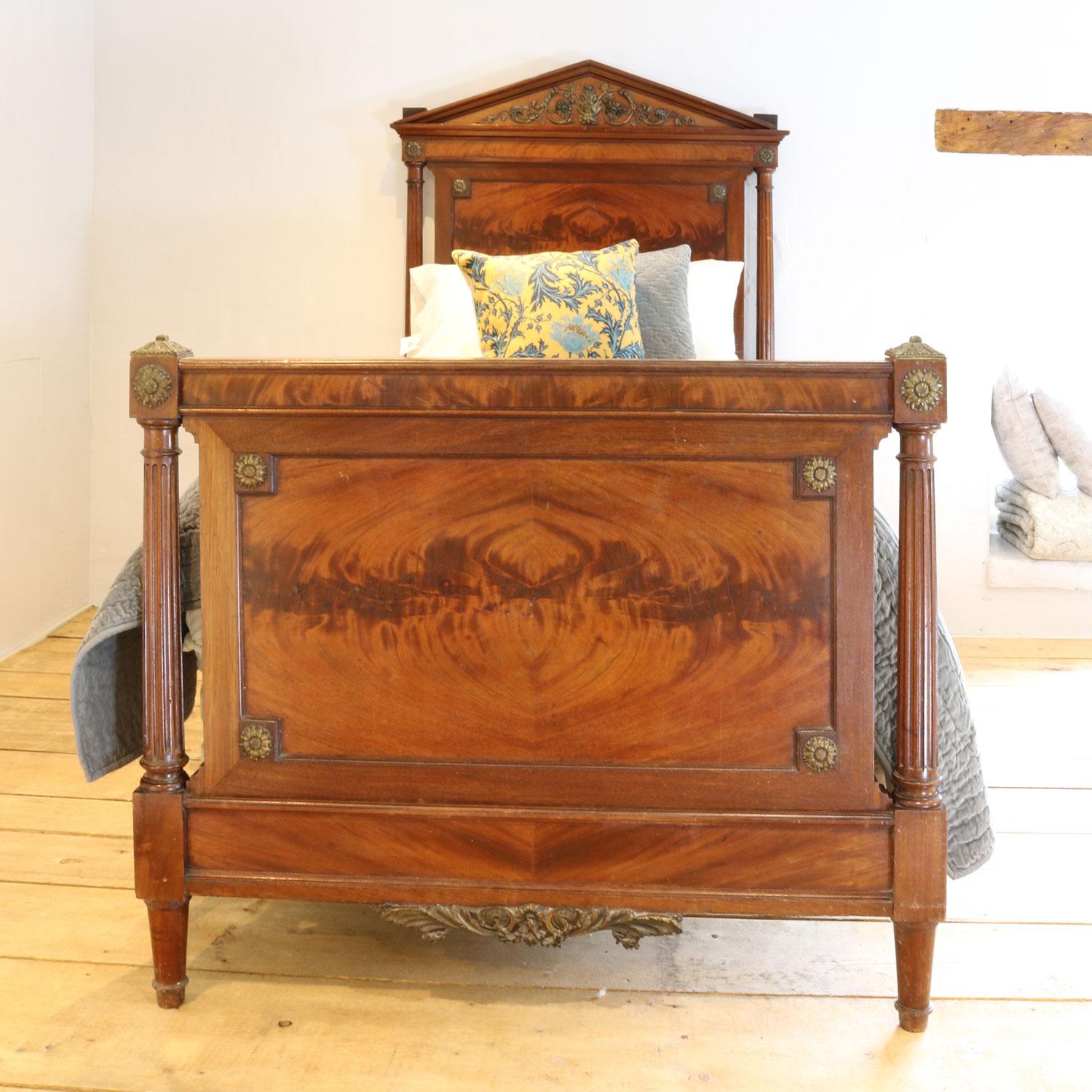 French Empire style antique bed made from burr mahogany, with decorative flower plaques on the head and foot board and ormelou detailing. 

This bed accepts a 3ft wide by 6ft 3in (or 6ft 6in long) base and mattress.

The price is for the bed