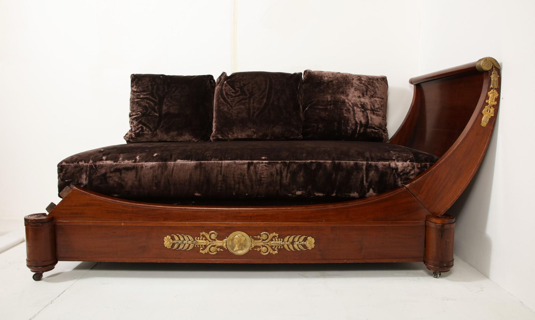 French Empire style mahogany daybed on casters with ormolu gilt bronze mounts and chocolate velvet upholstery.