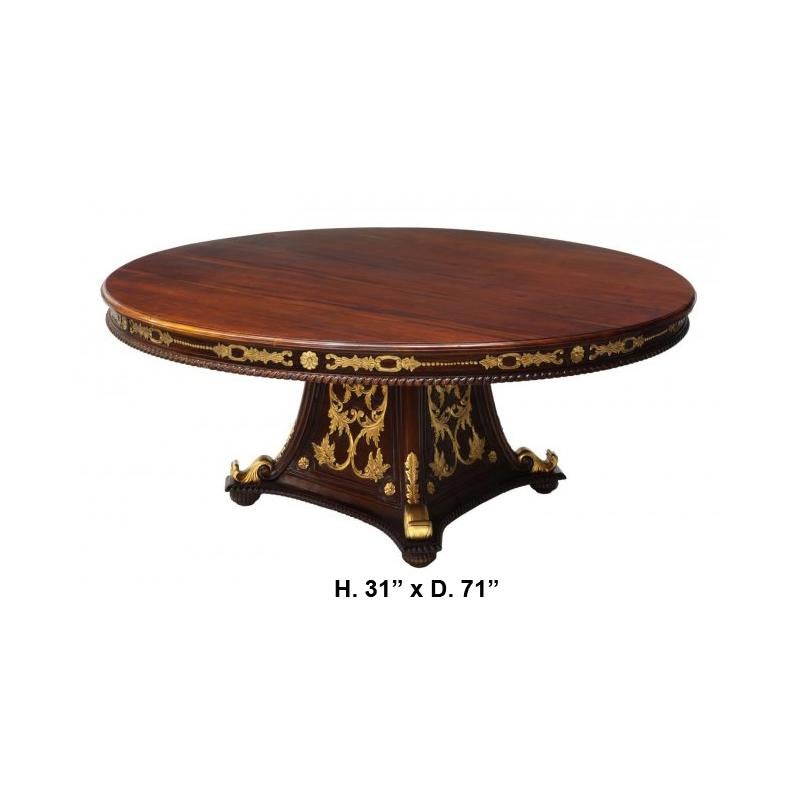 Imposing French Empire style mahogany parcel gilt round dining table. 
The beautiful and large round mahogany top is over a moulded frieze with carved giltwood foliage and scrolls, over a pedestal support decorated with finely carved scrolling