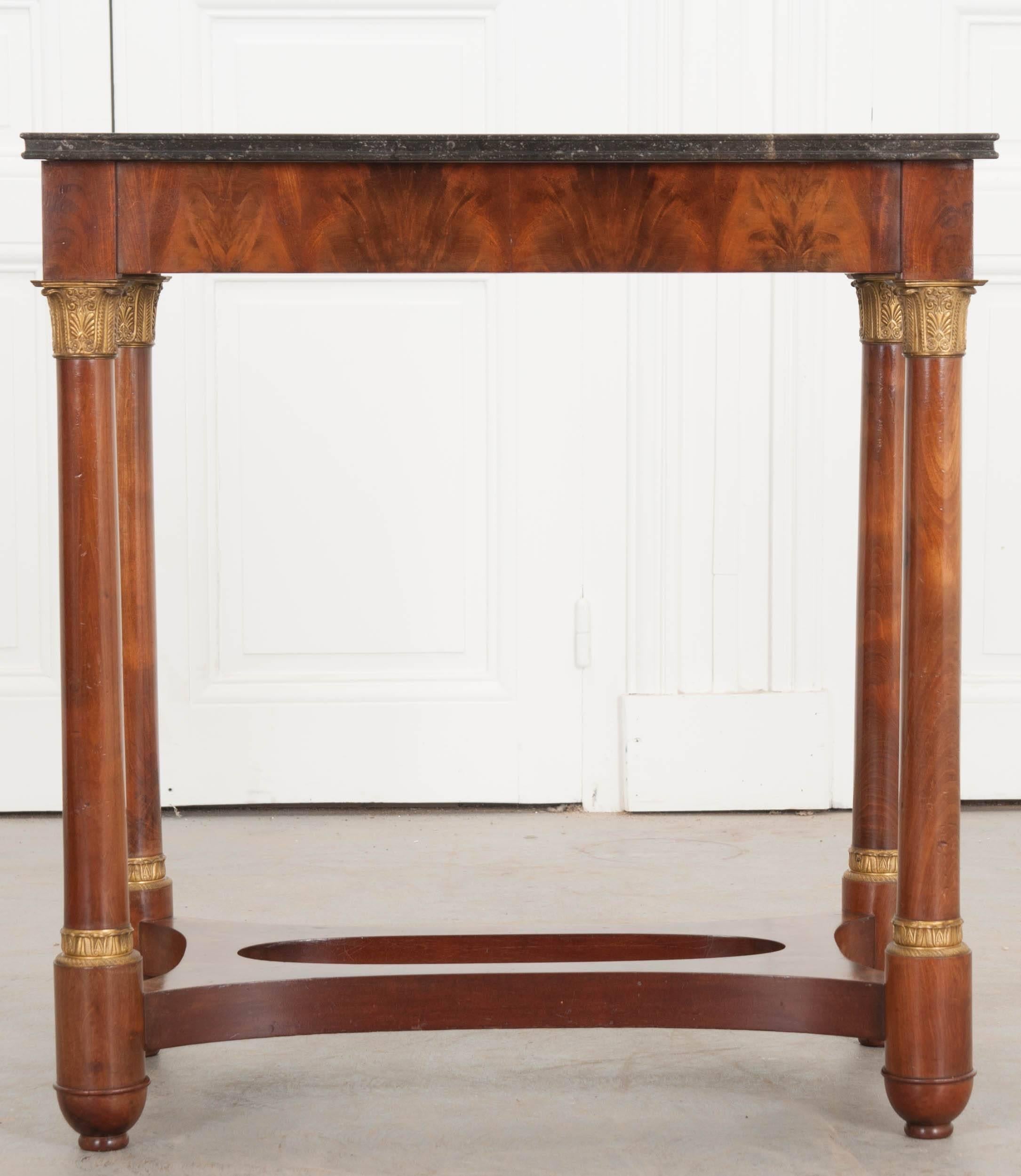 A fantastic mahogany Empire style table from France. Made at the beginning of the 20th century, this excellent little table has a beautiful black marble top that contains tiny fossilized creatures throughout. The marble is in terrific antique