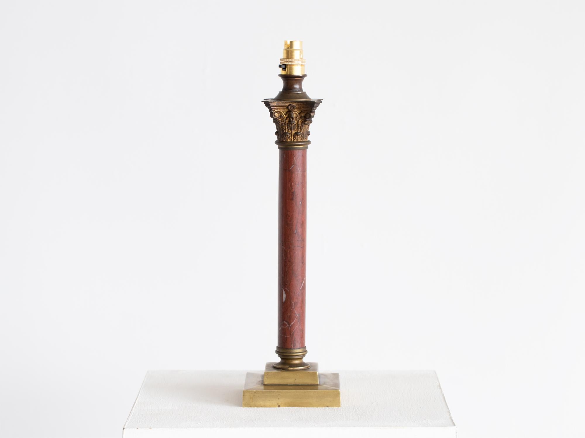 Lampe de table à colonne en marbre rouge avec chapiteau corinthien en métal doré sur une base en laiton à gradins. Français, début du 20e siècle.

Hauteur avec abat-jour : 65 cm (25.6 